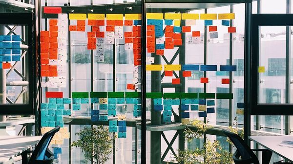Post-it notes stuck up on a glass wall in a modern office.