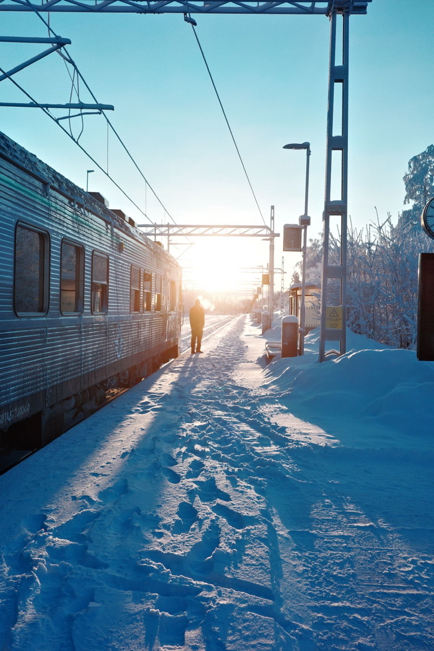A snow-covered railway platform in low winter sunlight