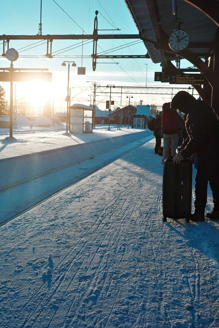 Travelers waiting on a snowy railway platform in morning light