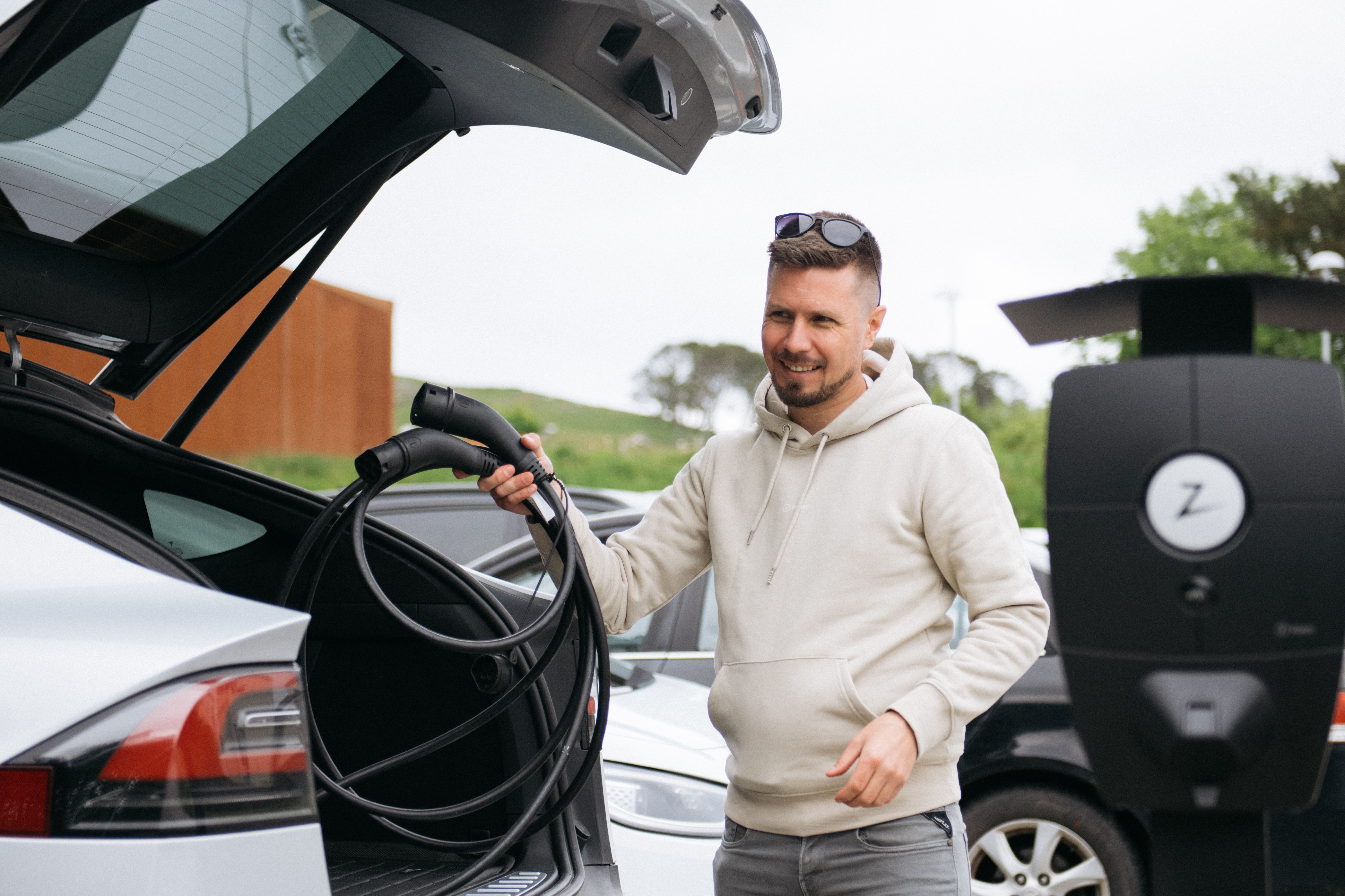 Bilde av en mann som legger en ladekabel i en bil