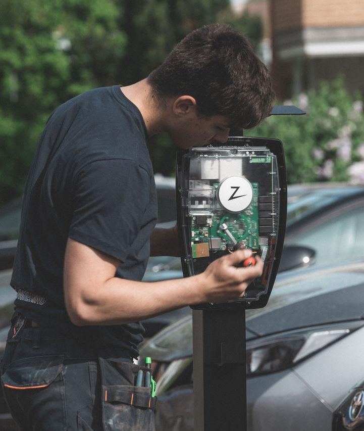 En mann som bruker en utendørs ladeboks med logo fra Elaway på
