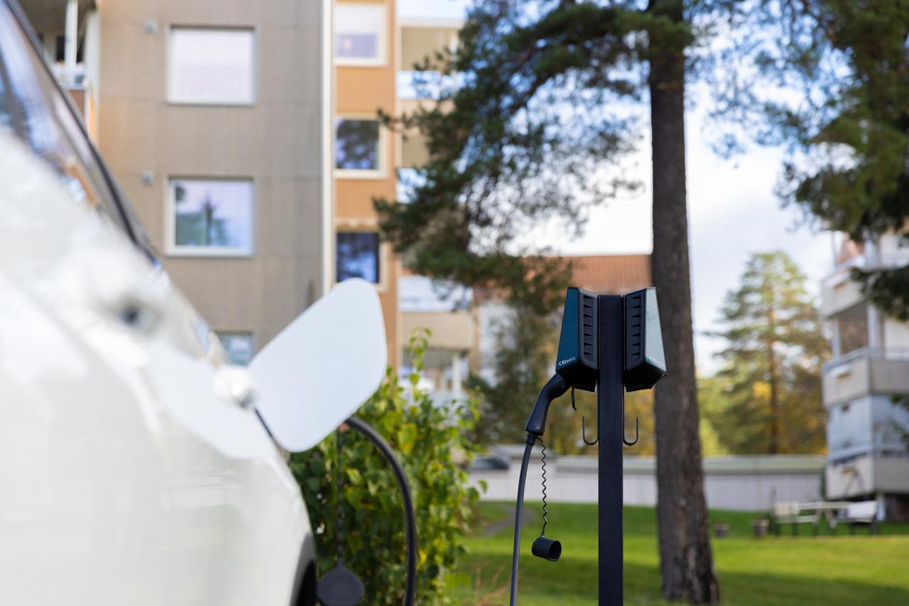 Bilde av en elbil, utendørs ladeboks og boliger