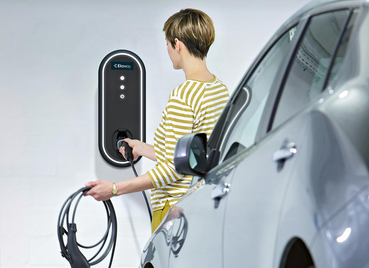 Kvinne i gulstripete genser lader bil i garasjeanlegg