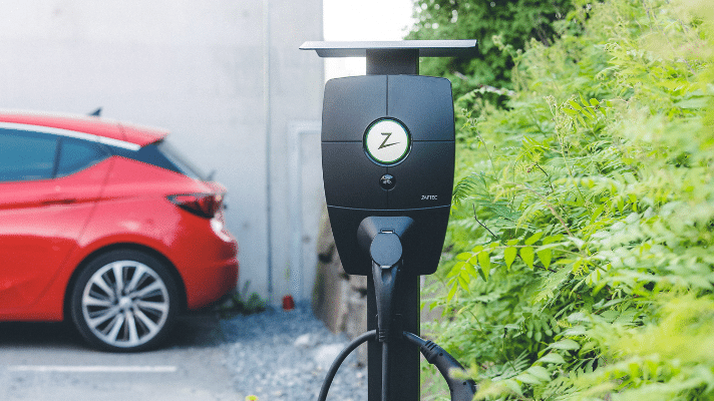 Bilde av en ladeboks utendørs foran en rød elbil