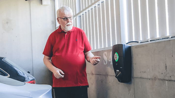 Bilde av en mann ved siden av en ladeboks innendørs i et garasjeanlegg