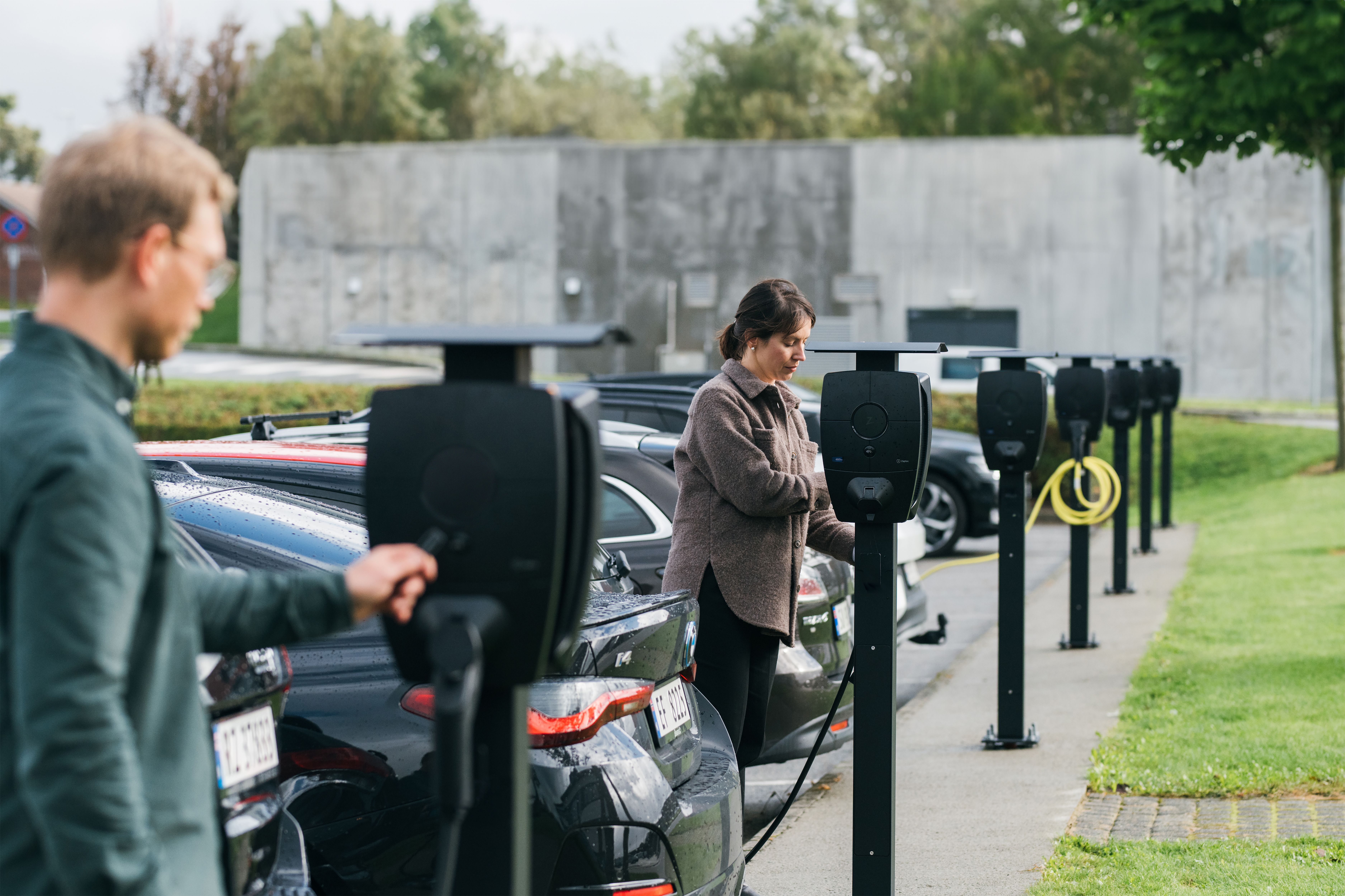 Bilde av to personer som lader hver sin elbil