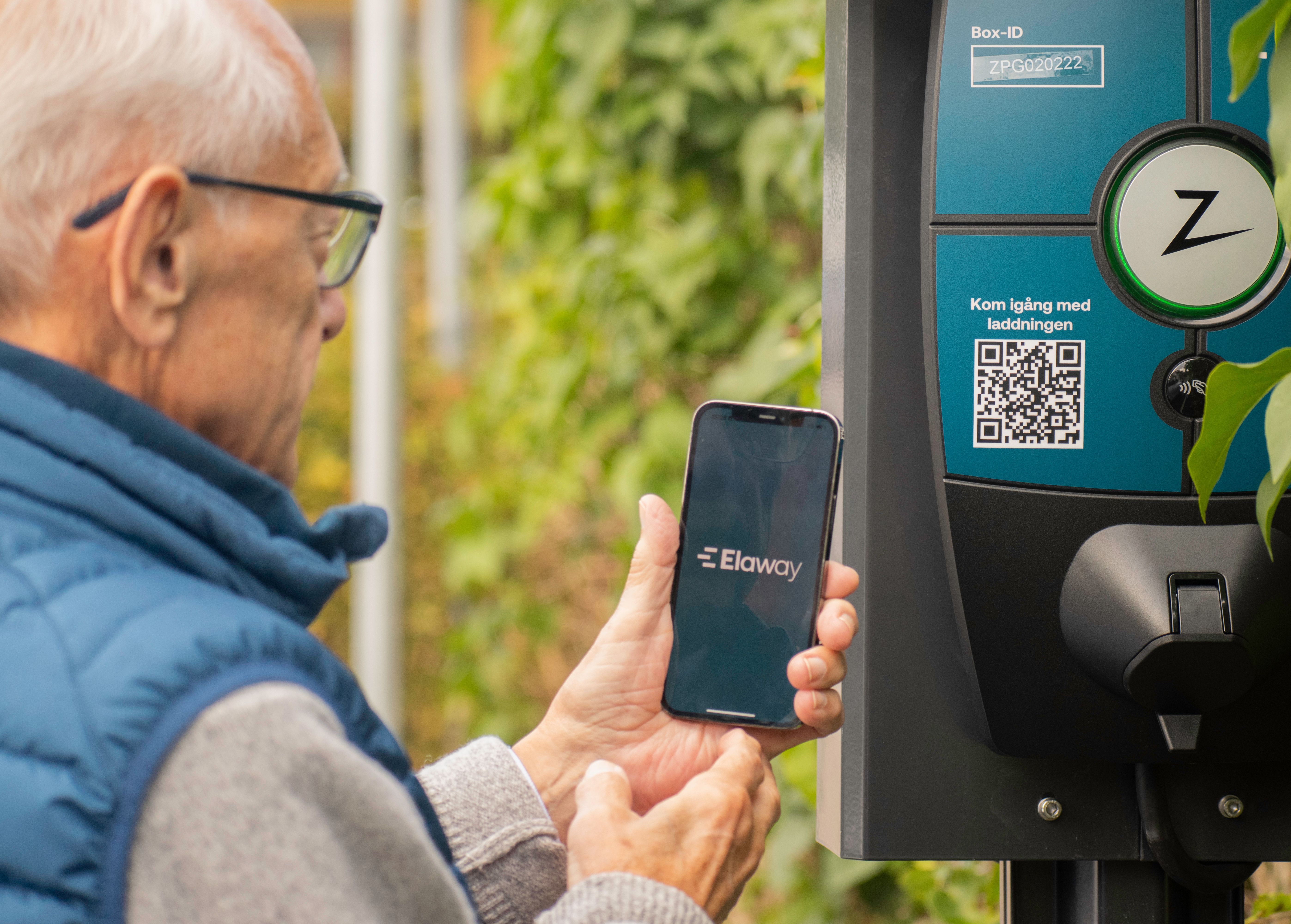 En mann som bruker Elaway sin app i mobilen til å lade elbilen