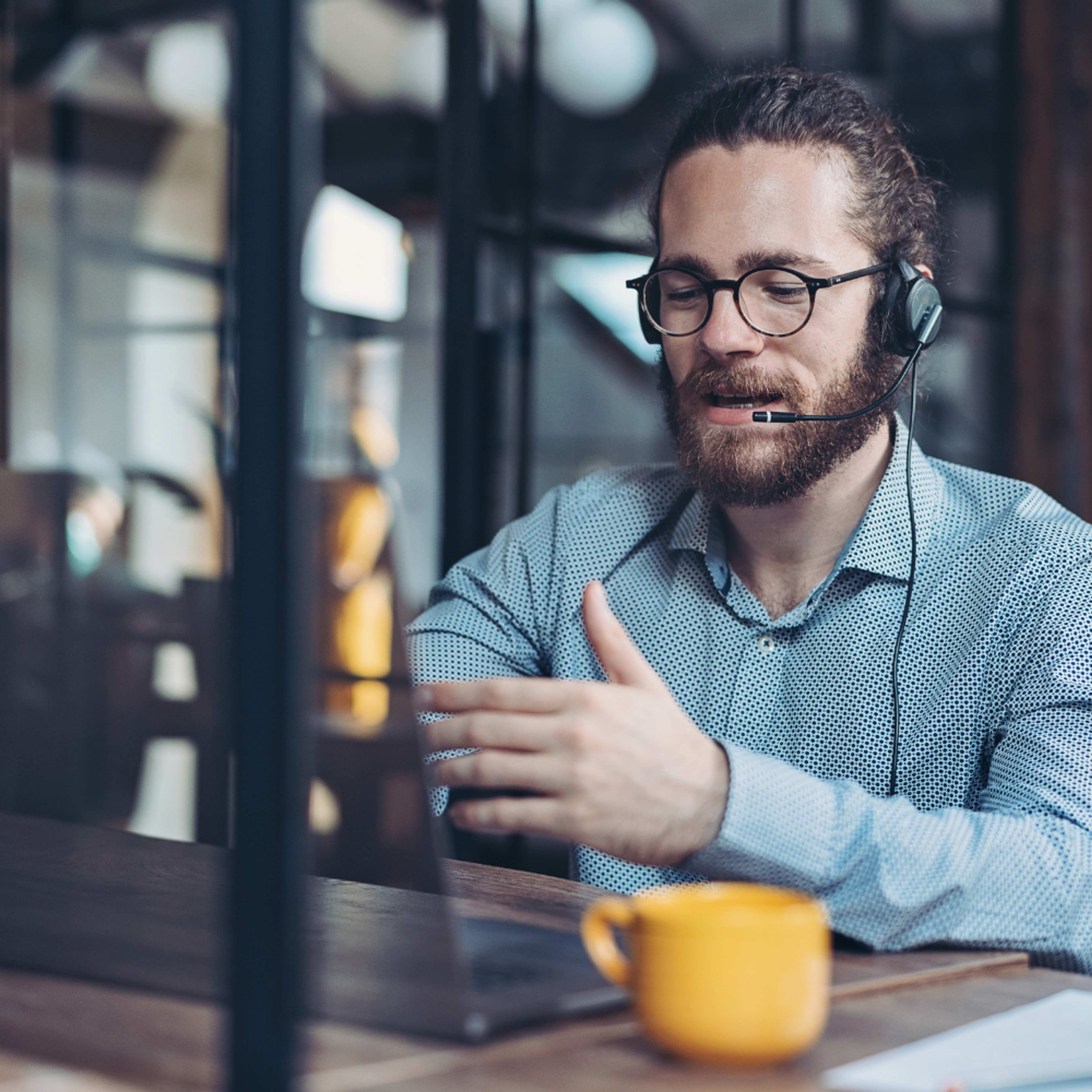 IT support man with beard at desk with yellow mug
