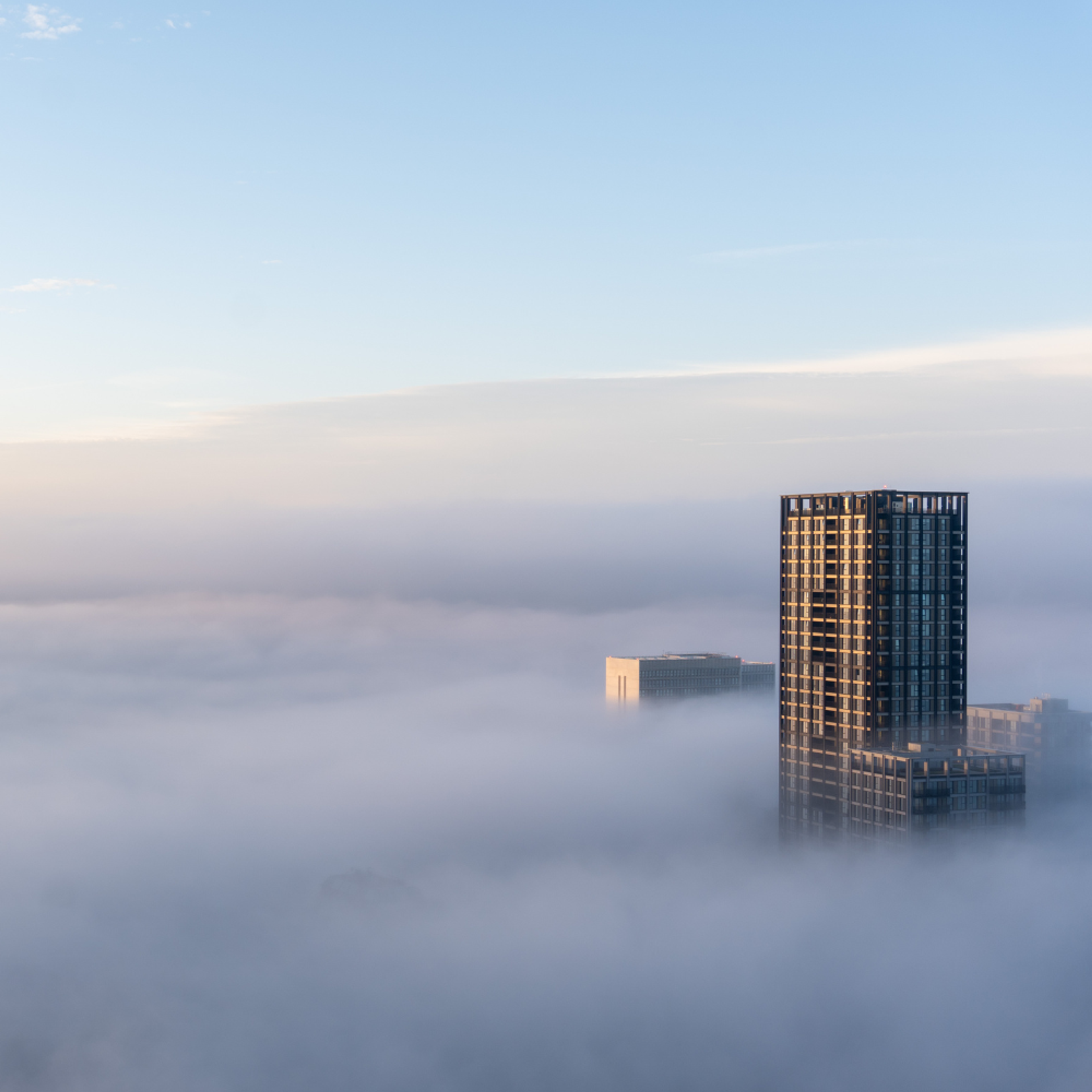 The top of a skyscraper appearing above the clouds