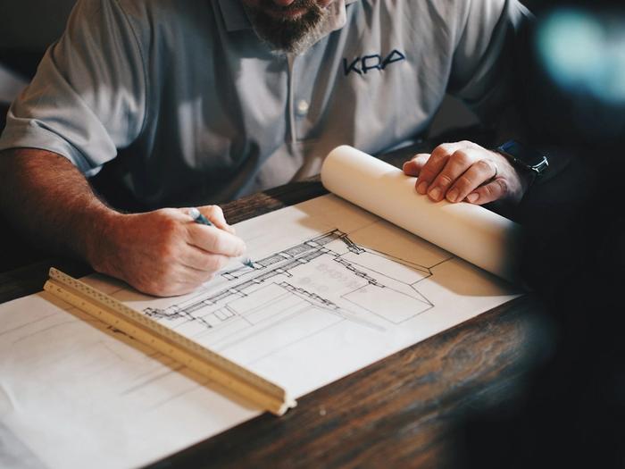 Construction blueprints, measuring tools, and planning documents on a desk