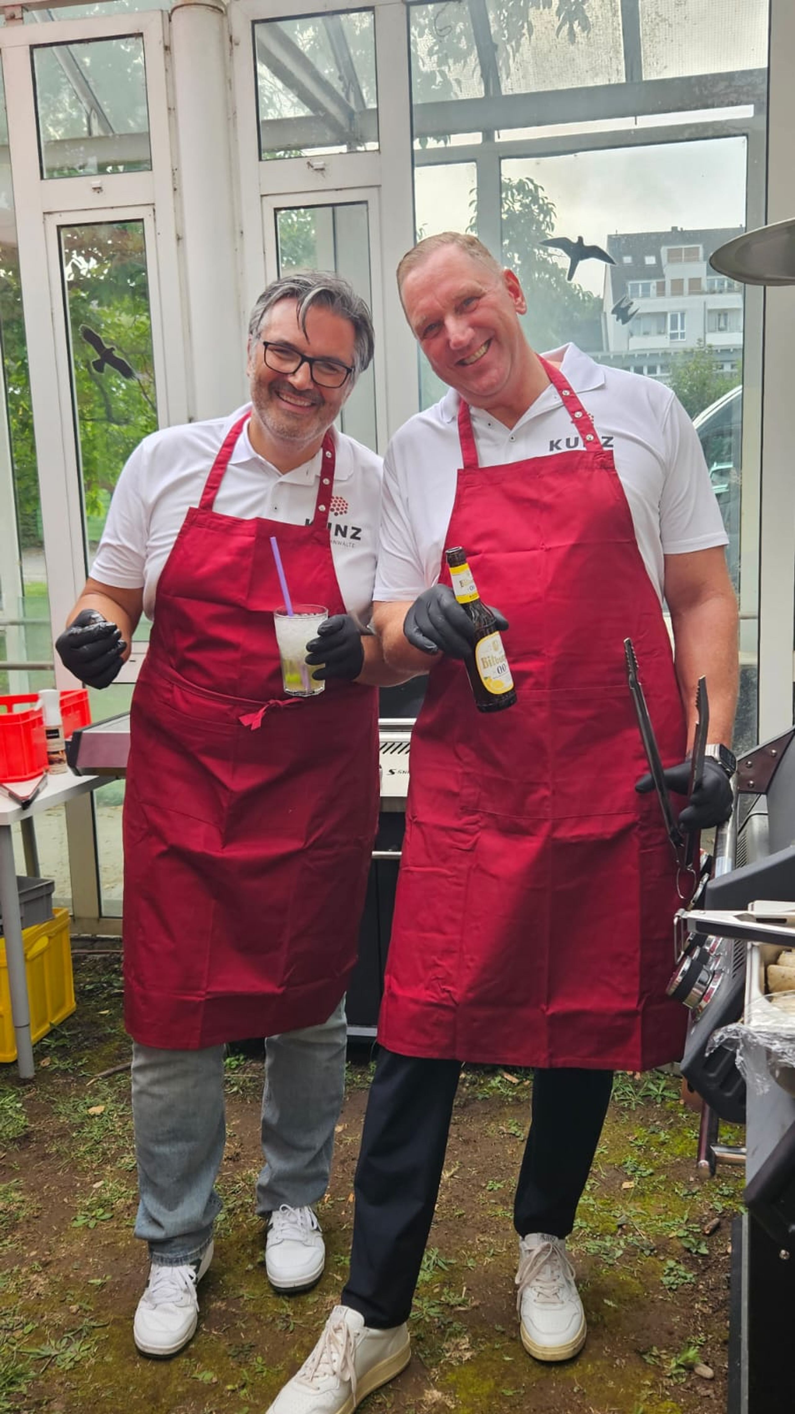 Zwei Kollegen in roten Grillschürzen