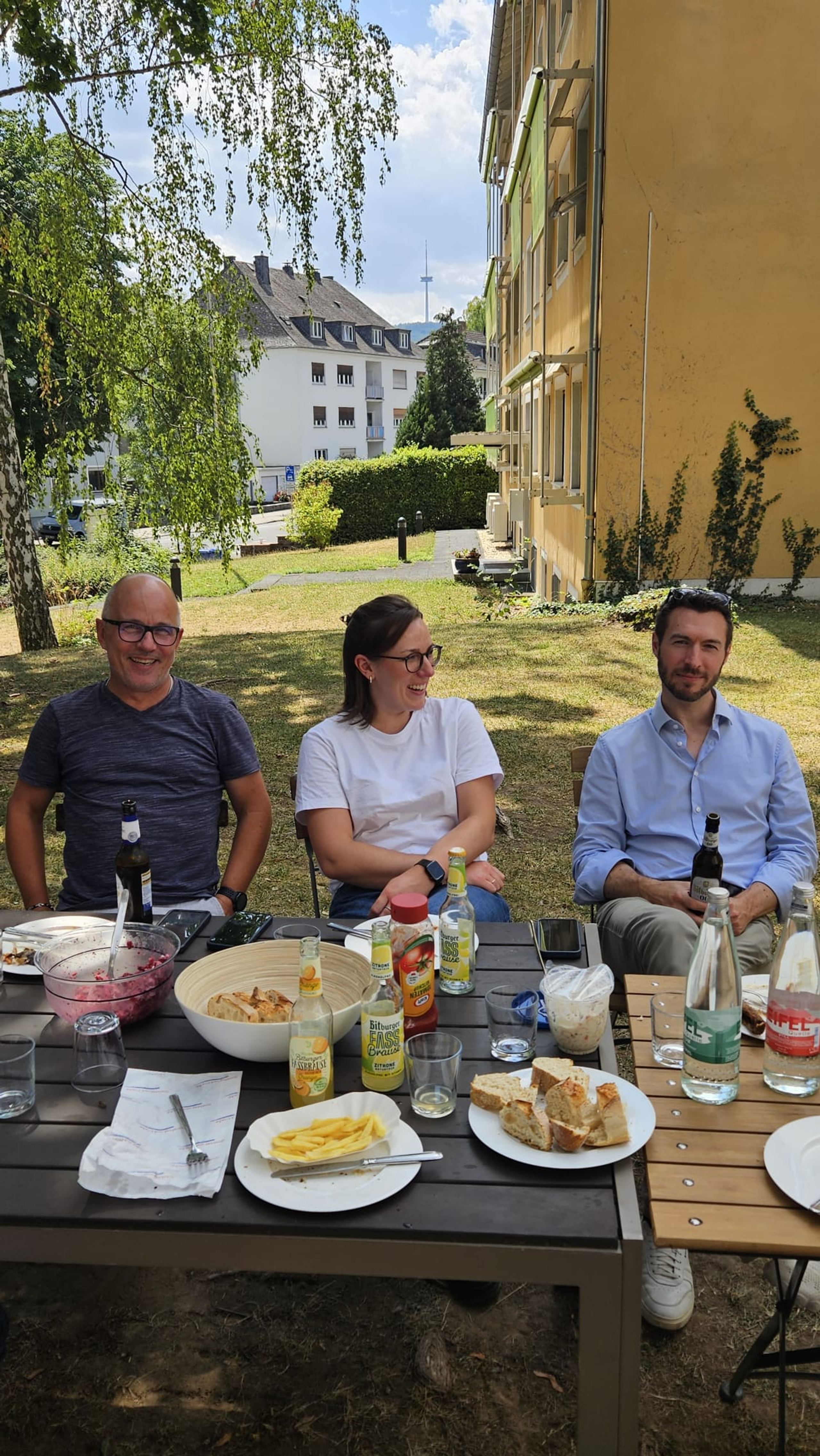 Drei Kolleginnen und Kollegen beim Essen im Garten