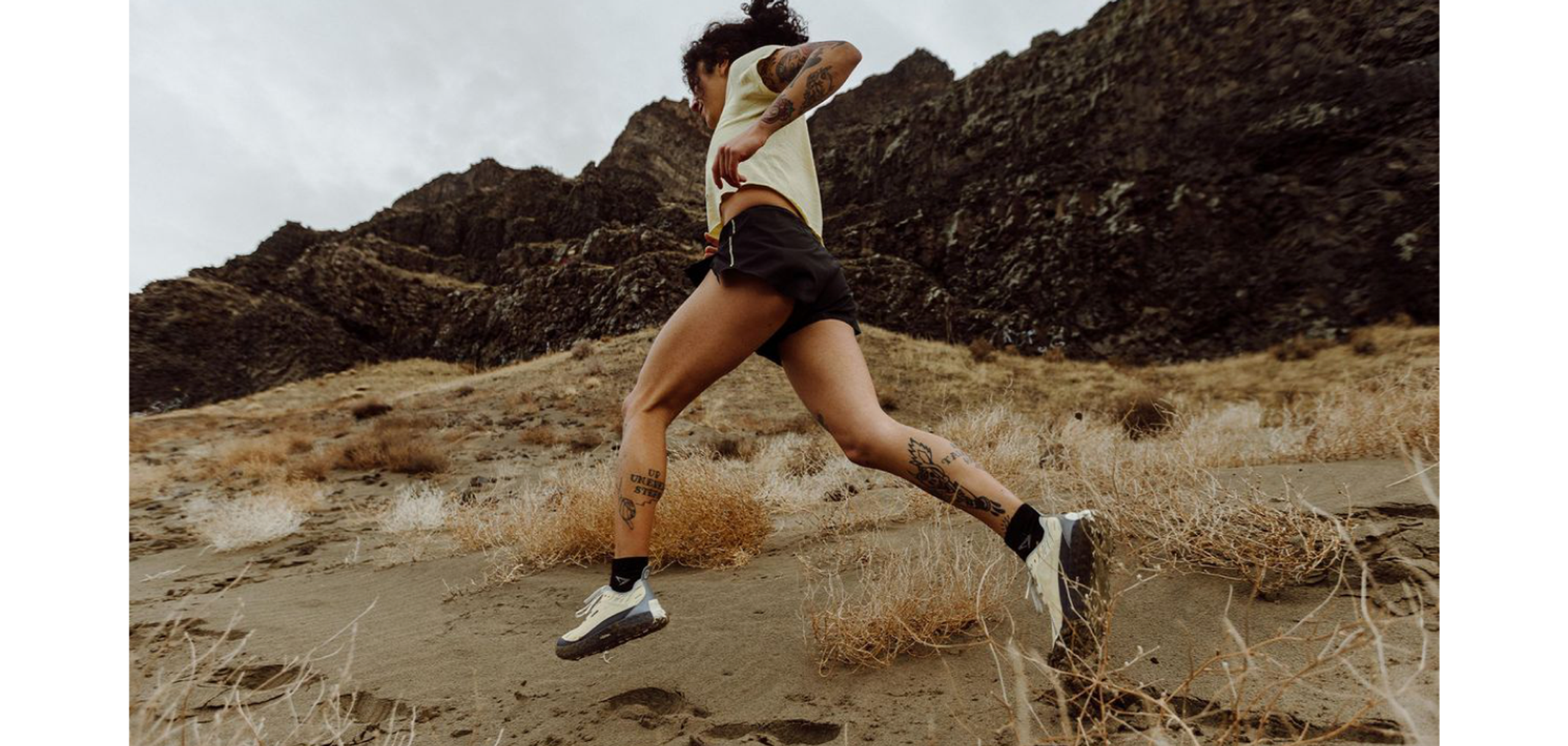 Trail runner sprinting across a desert mountain landscape