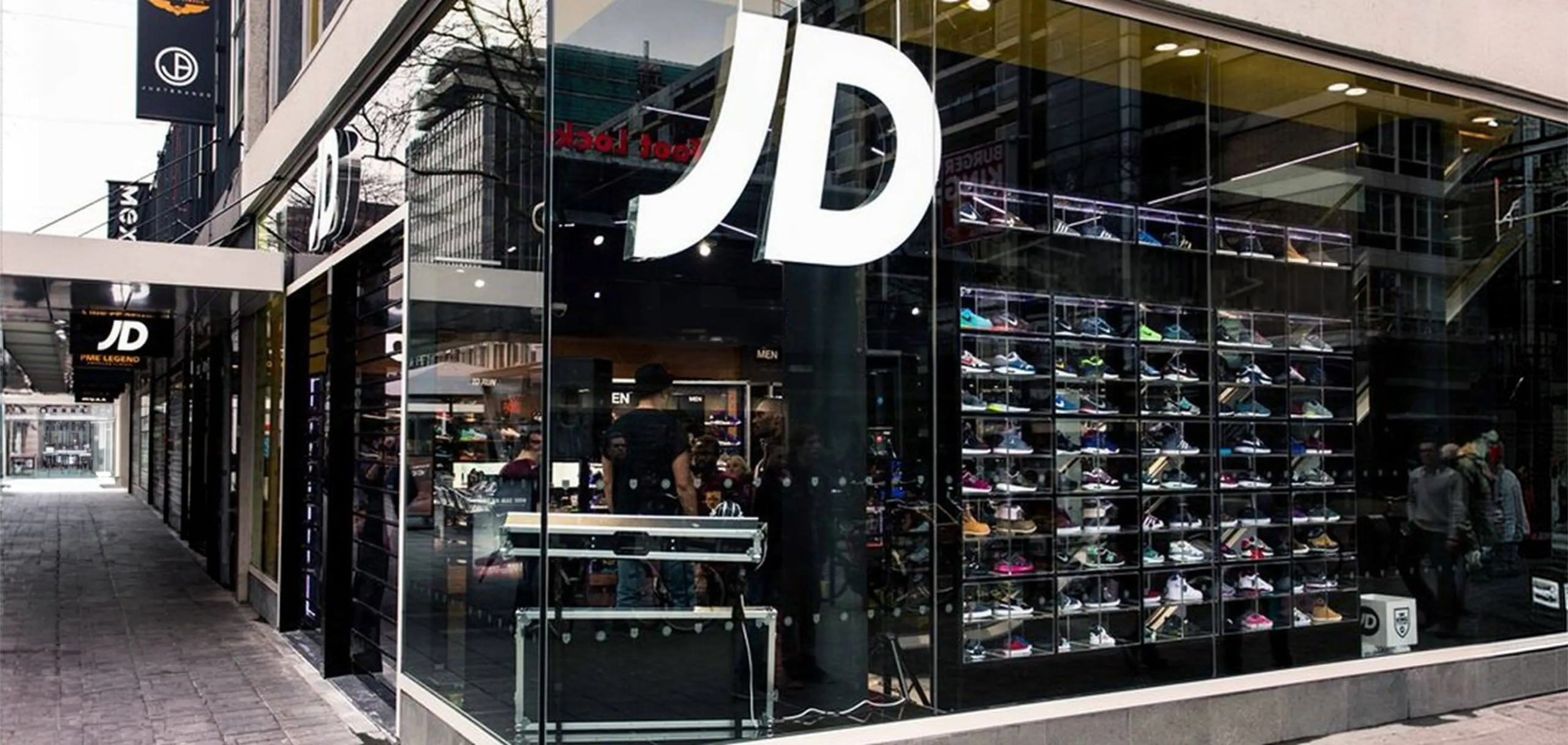 JD Sports storefront with a glass shopfront and sneaker wall