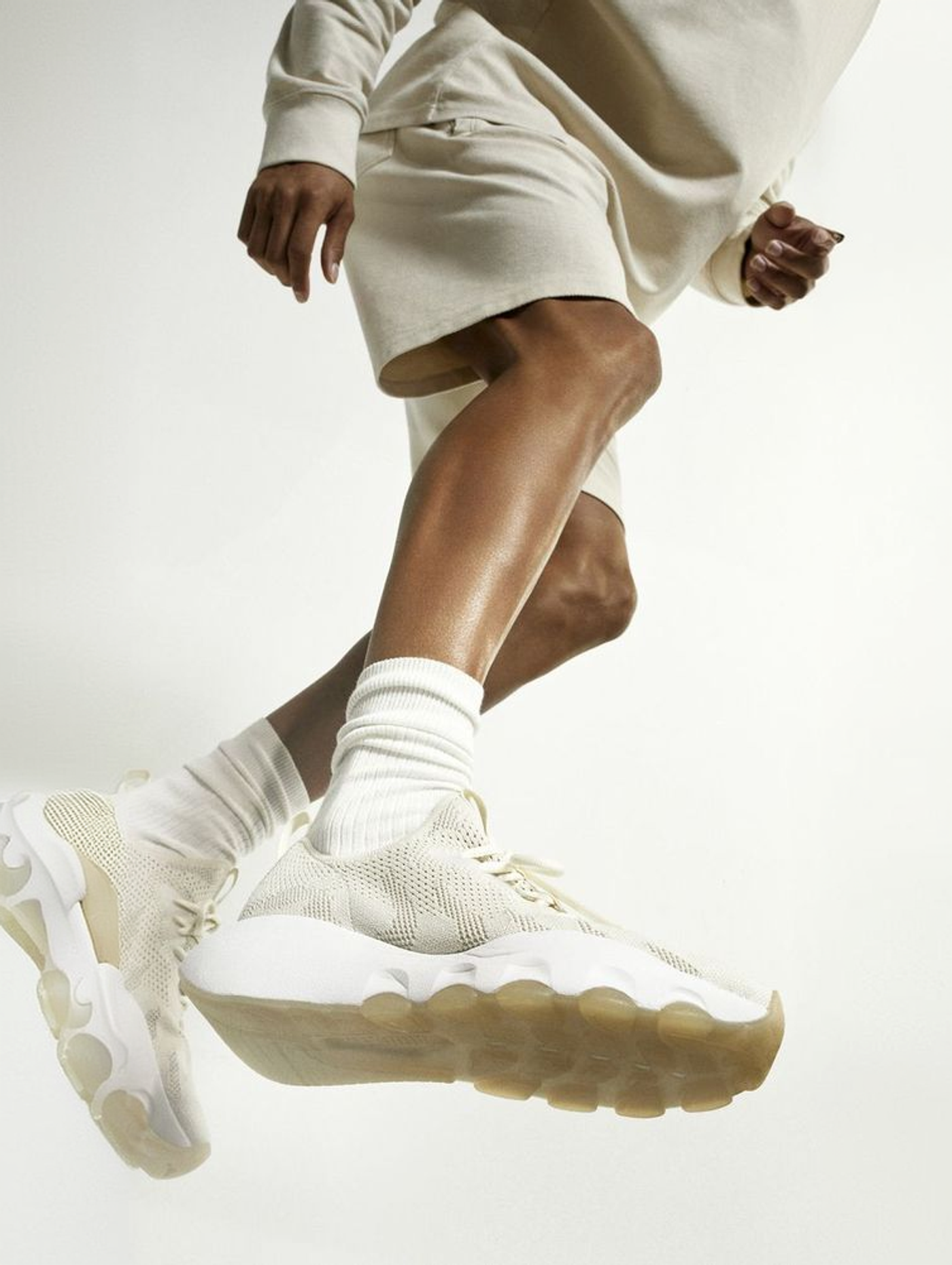 Person wearing cream-colored sneakers mid-stride