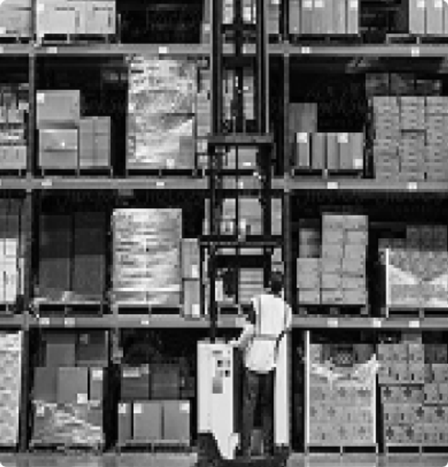 Warehouse worker between tall shelves of stacked boxes