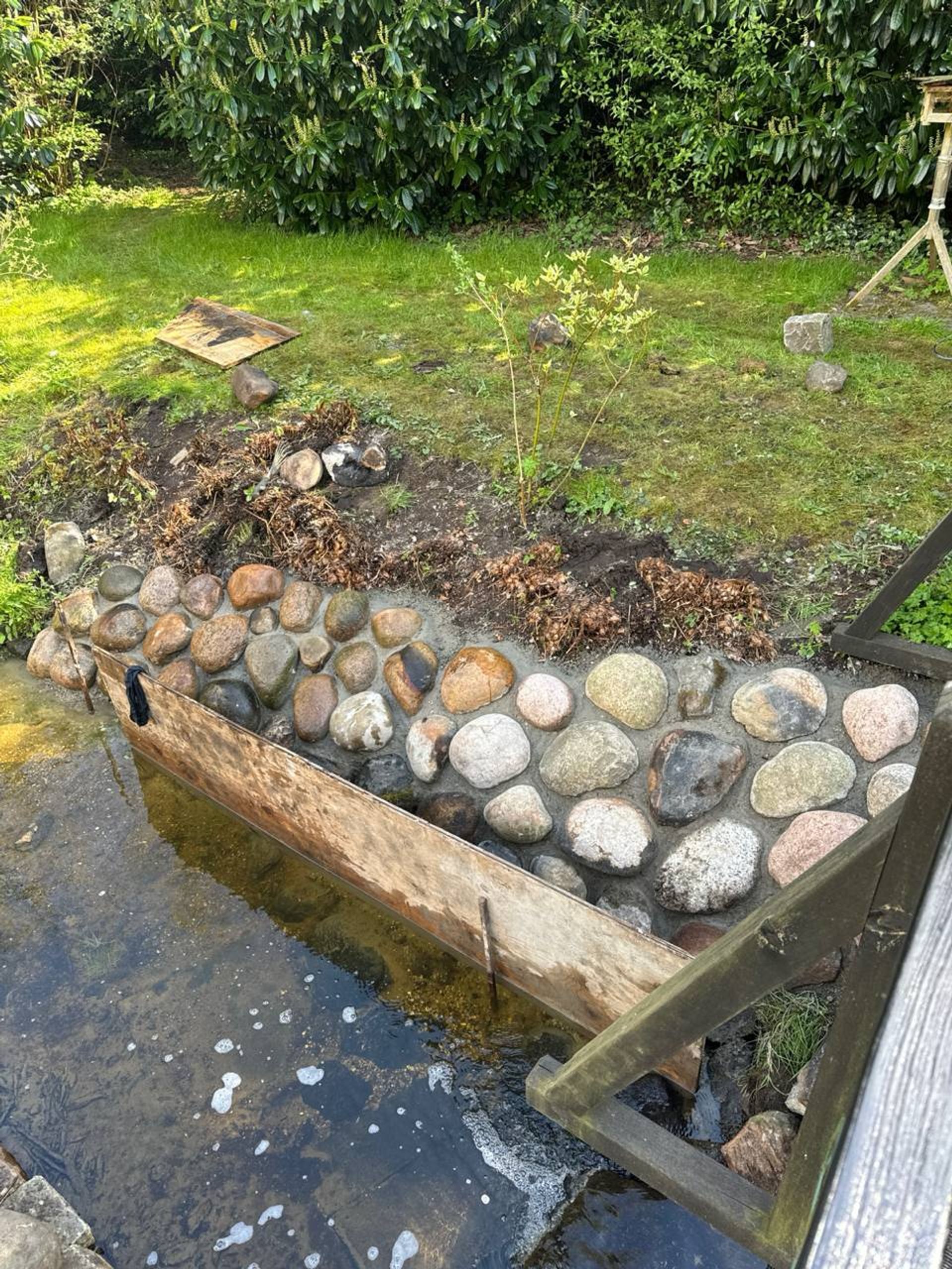 Støttemur i natursten ved vandløb i have
