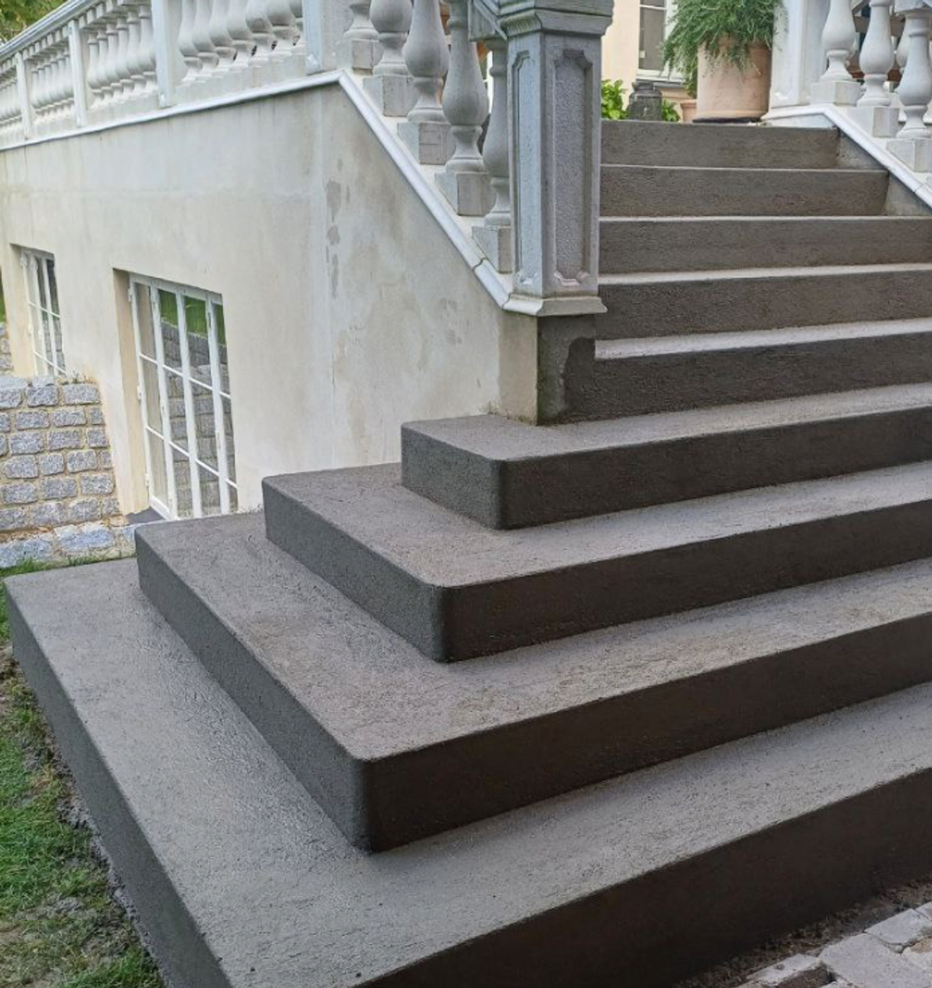 Nybelagte betontrin foran bolig med hvid balustrade