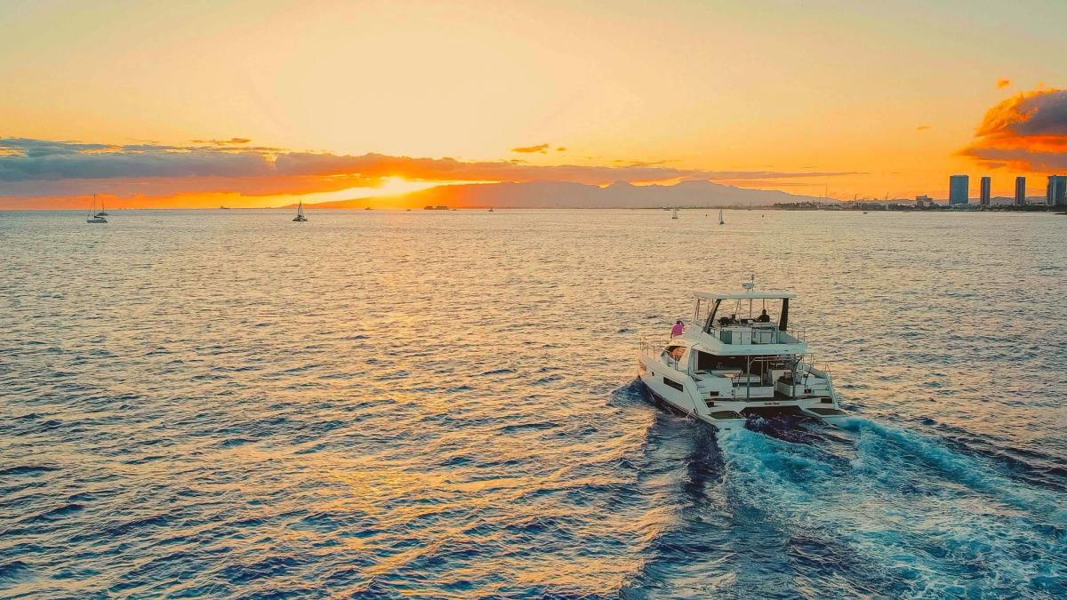 Power catamaran sailing toward Waikiki at sunset