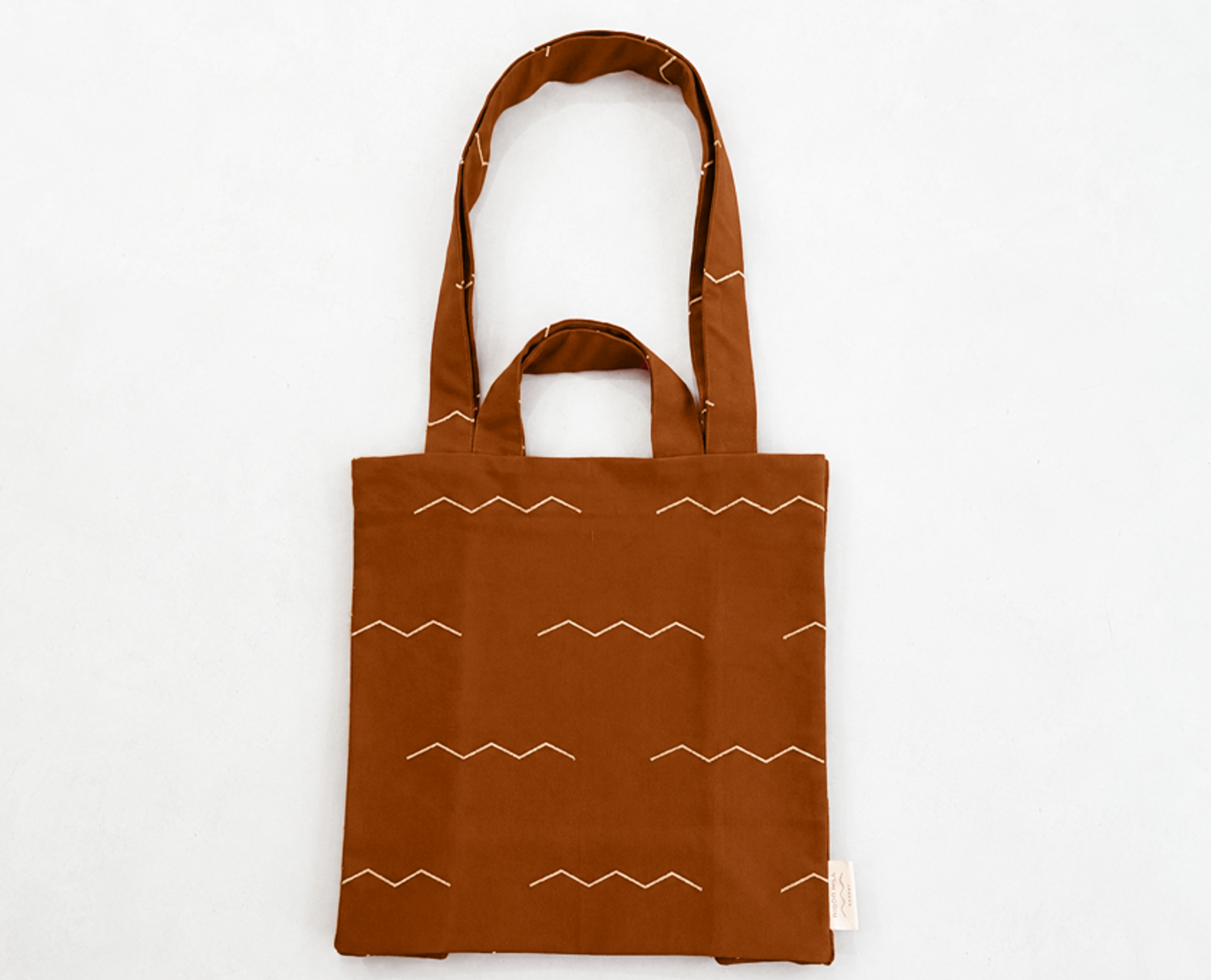 Double Handle Bag in dyed-to-match rust color canvas with white embroidered design