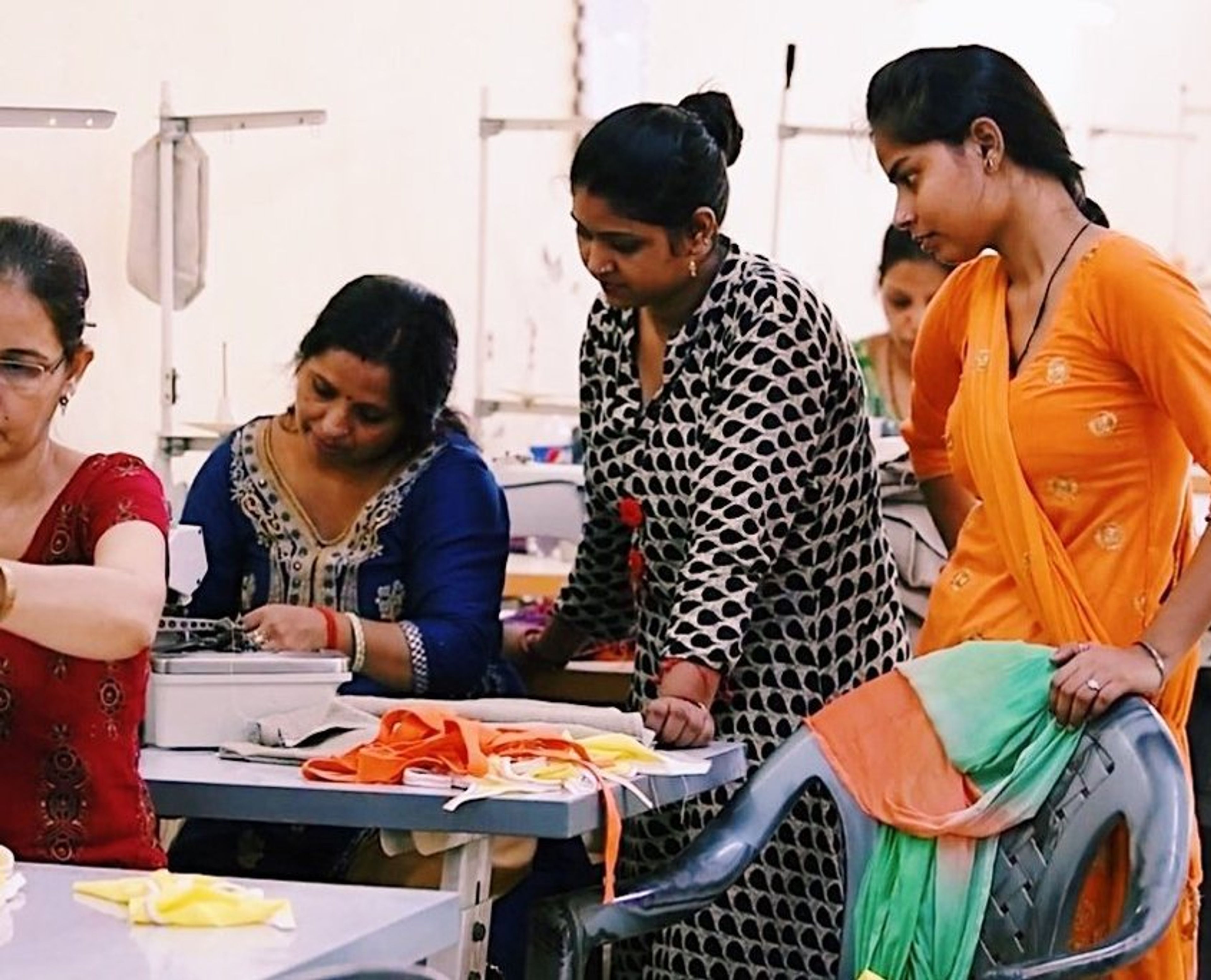 Women learning textile or garment design in a workshop classroom setting.
