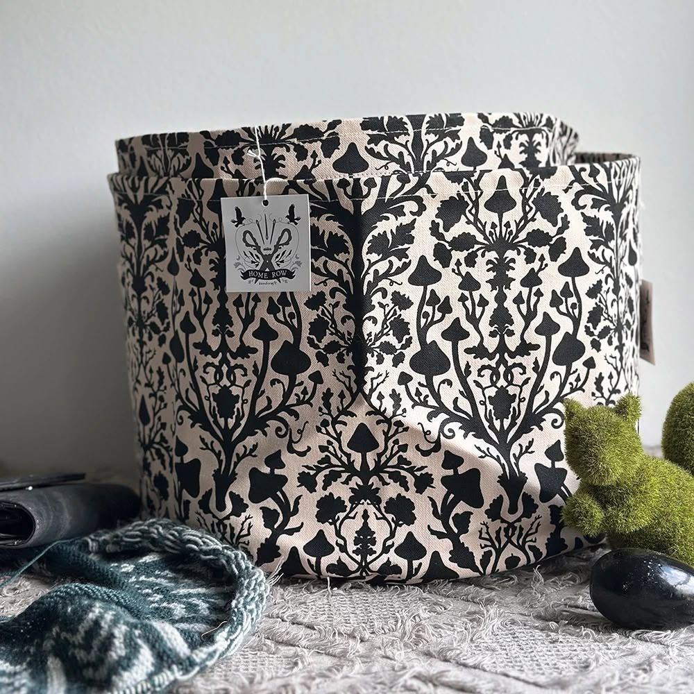 Decorative fabric storage basket with black damask pattern, label, and surrounding items.
