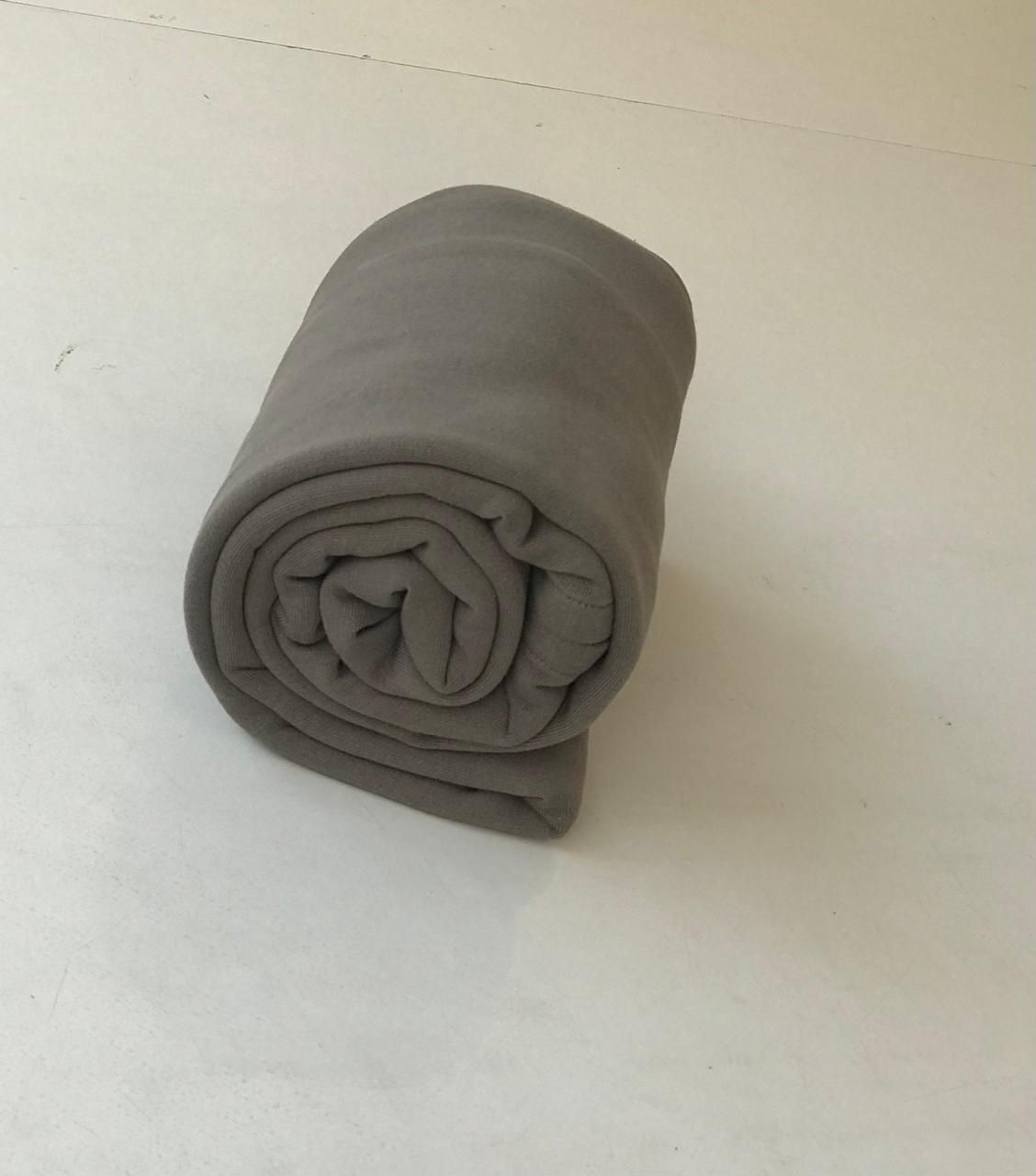 Rolled gray fabric or textile tightly wound into a cylinder on white surface.