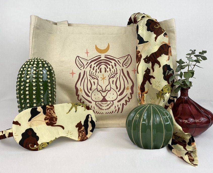 Canvas tote bag with tiger design surrounded by cacti, fabric scraps, and decorative items.