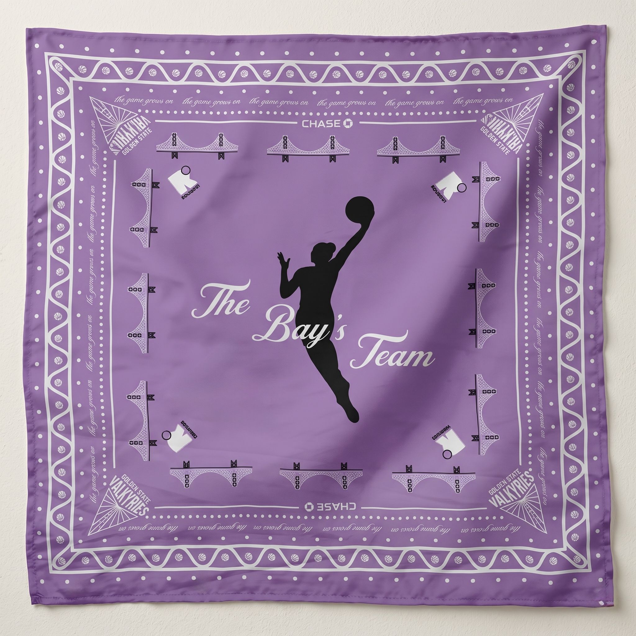 Lavender silk scarf featuring a black silhouette of a female basketball player dunking, titled 'The Bay's Team.' The design includes white Golden Gate Bridge icons, Golden State Valkyries logos in the corners, and a decorative patterned border."