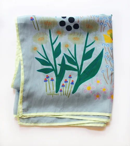 Folded fabric with botanical design: dandelions, wildflowers, sun, and insects.