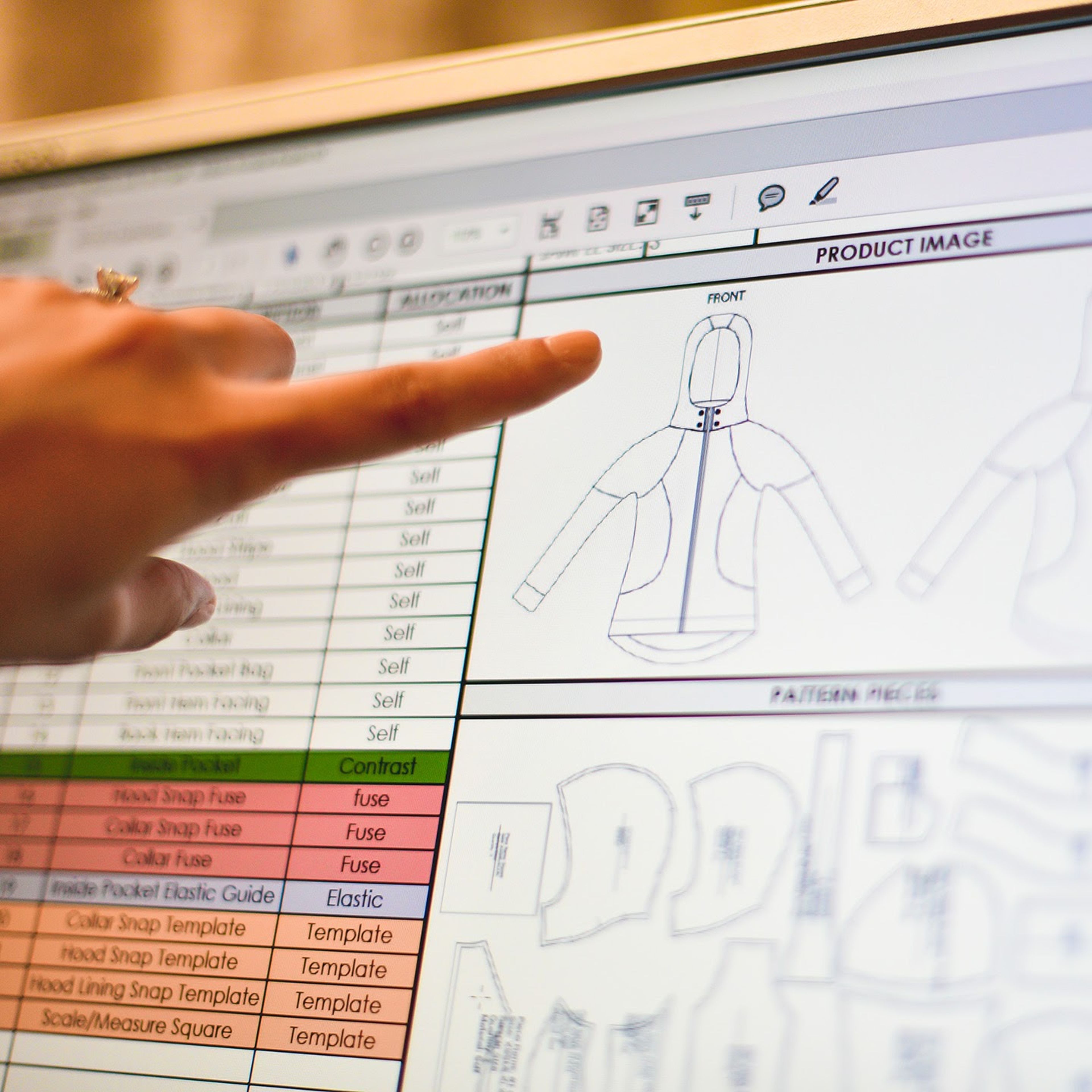 Person pointing at product design sketch of hooded jacket on computer screen.