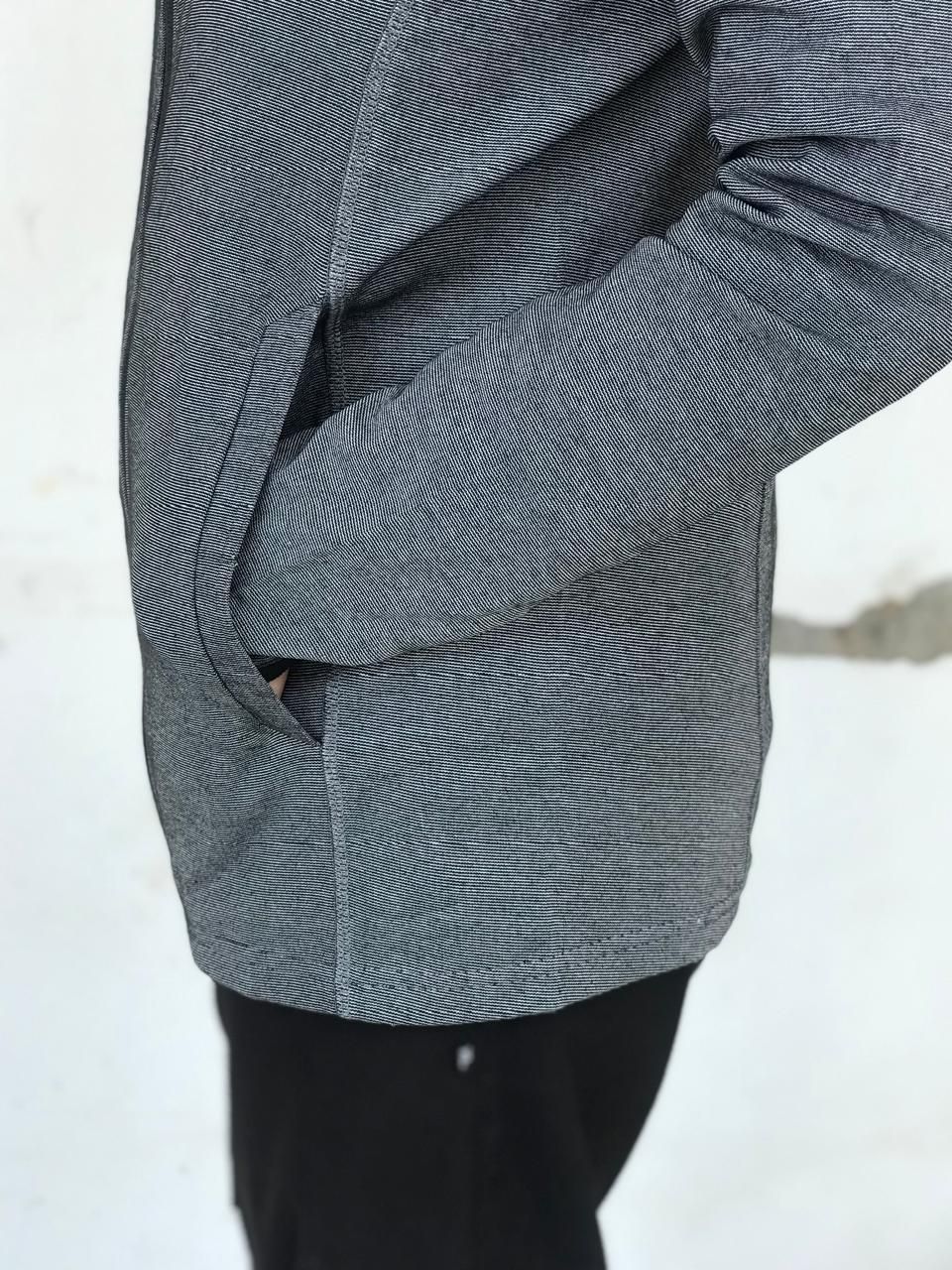 Person wearing gray textured jacket and black pants outdoors in winter.