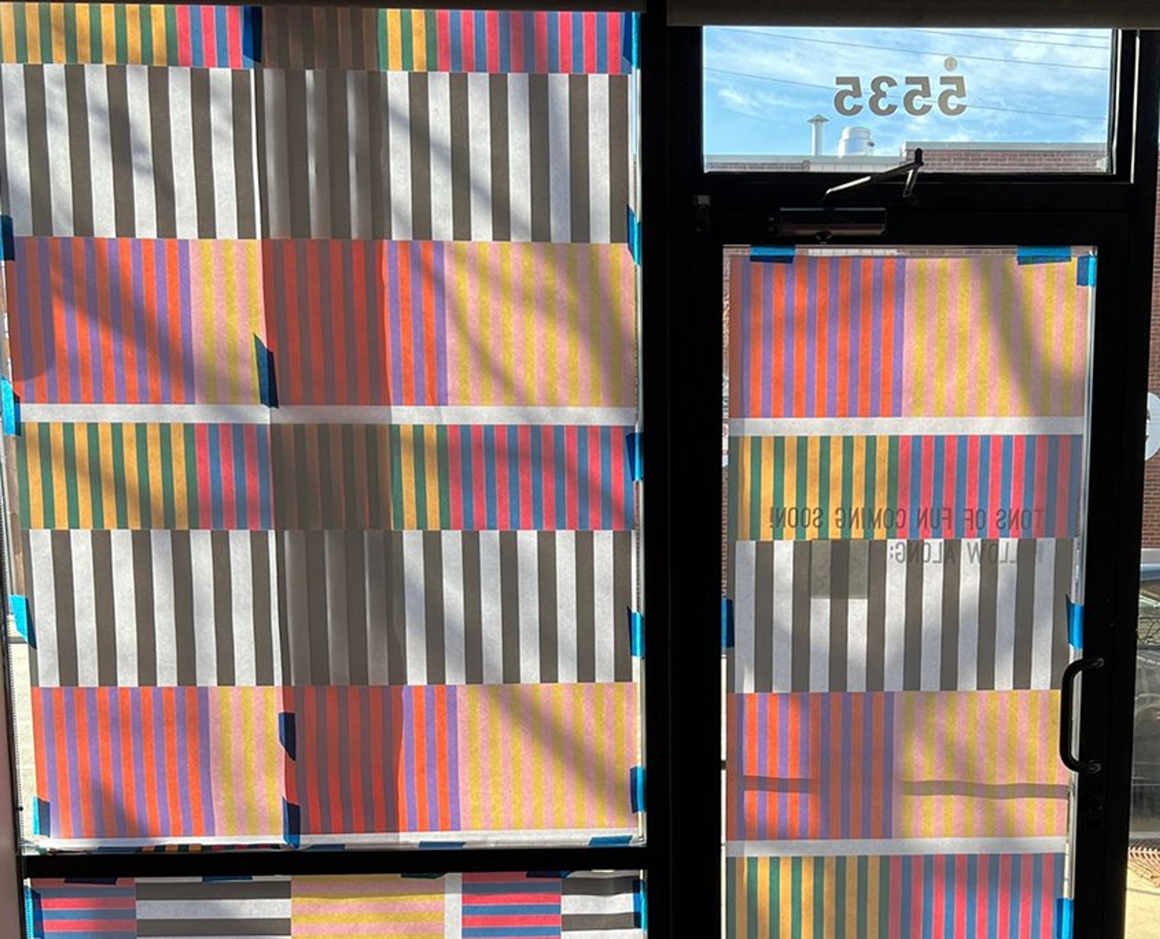 Colorful striped fabric samples displayed on windows of a storefront or showroom.