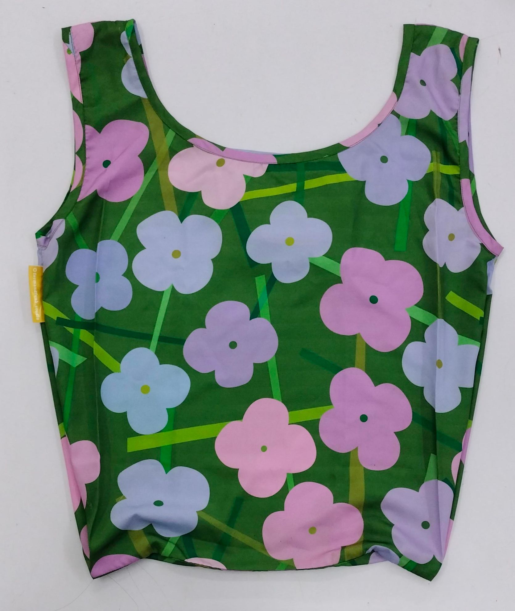 Sleeveless tank top with colorful flower pattern on green background.