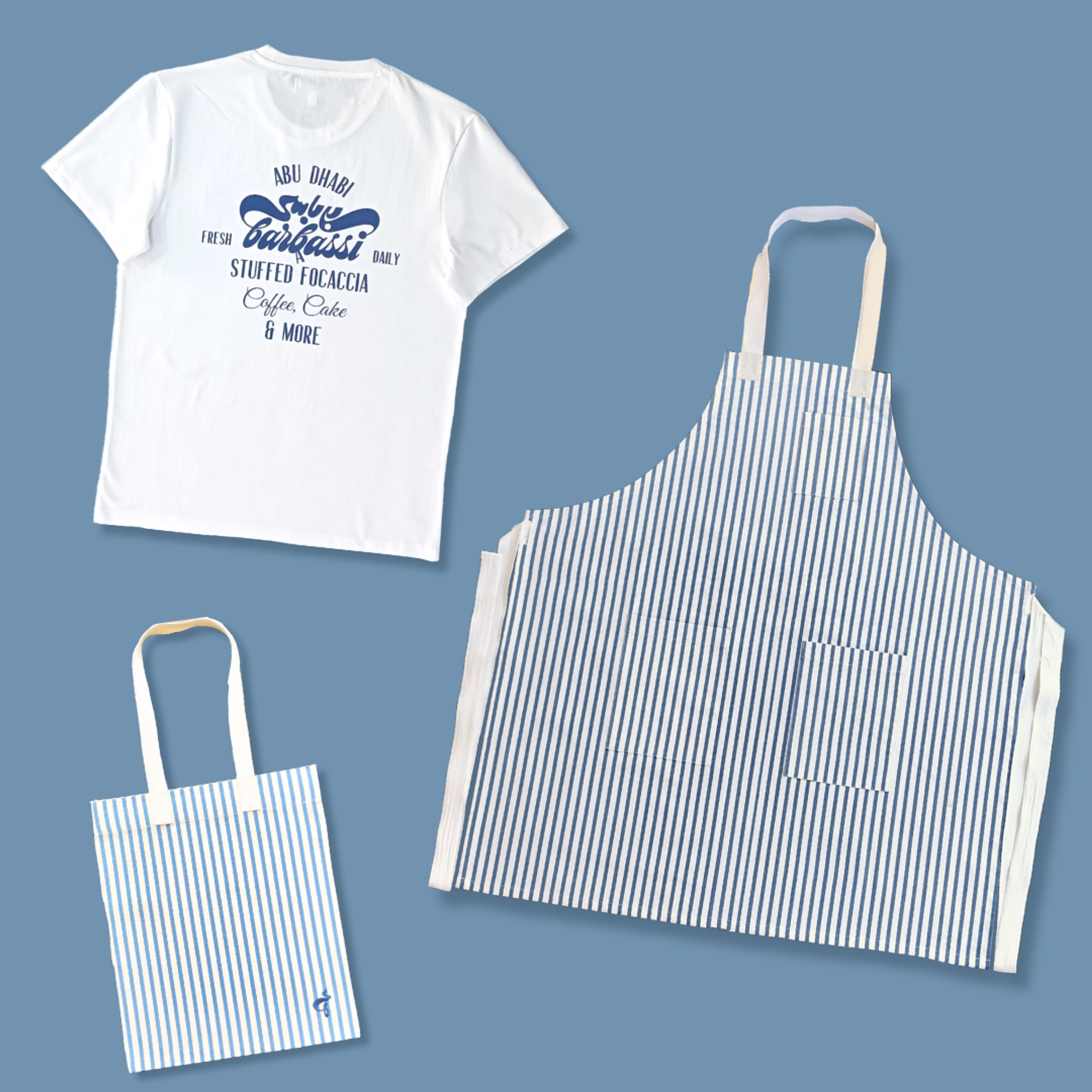 White t-shirt and blue striped apron and tote bag displayed on blue background.