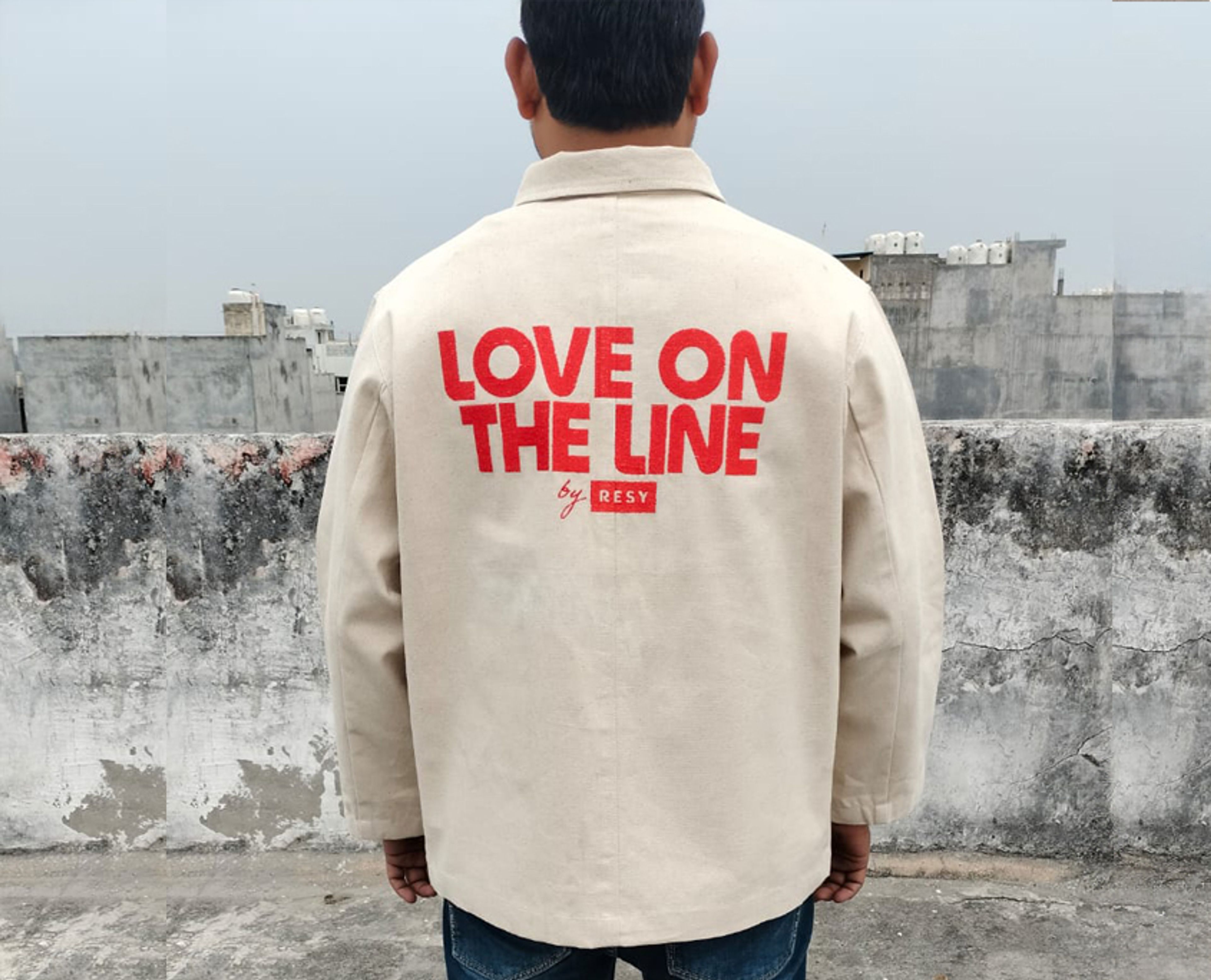 Café Chore Coat in natural canvas with a red embroidered design across the back.