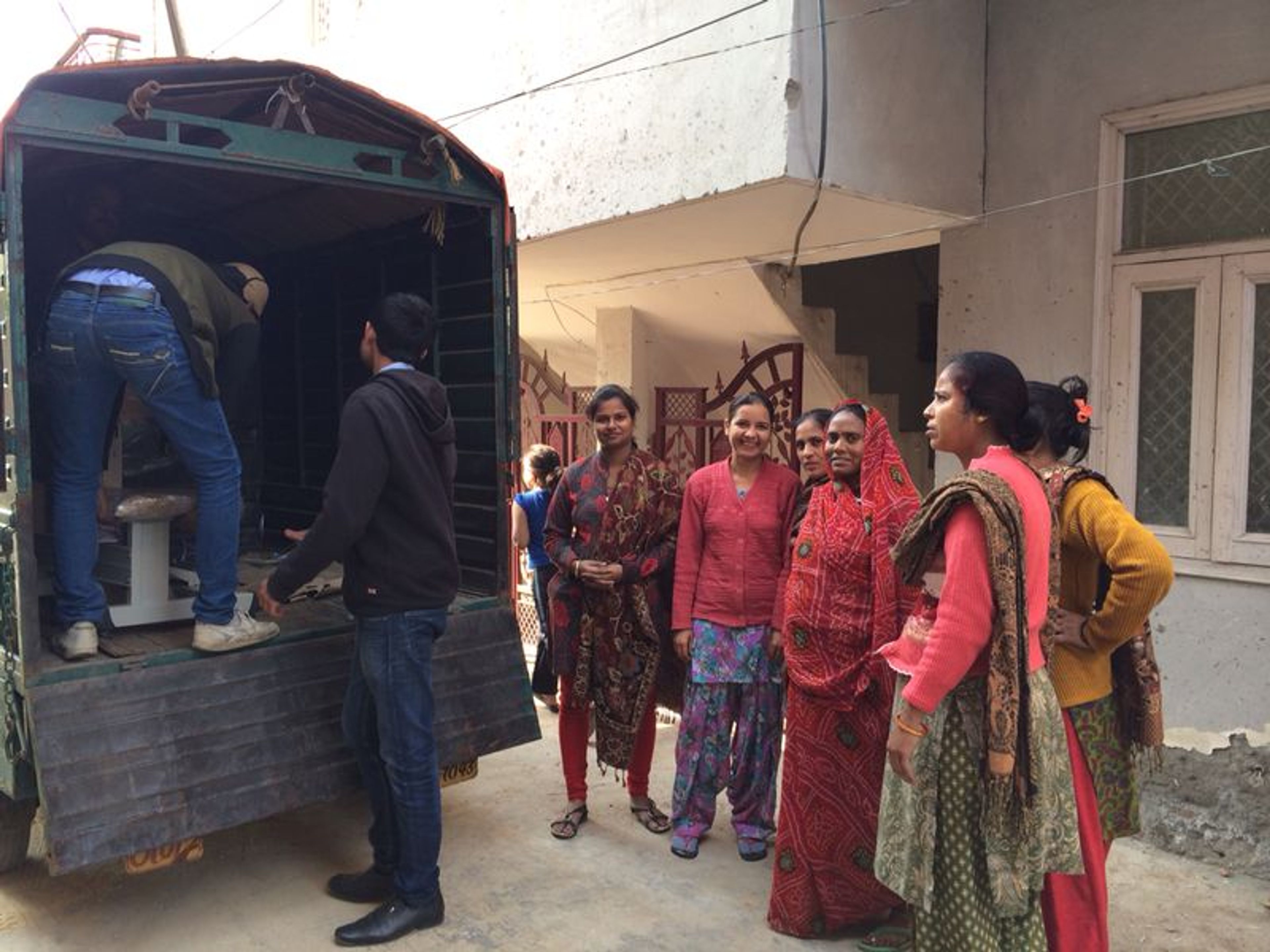 Group of women waiting outside mobile service truck in rural setting.