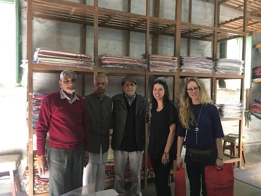 Five people standing together in front of shelving with stacked materials inside.
