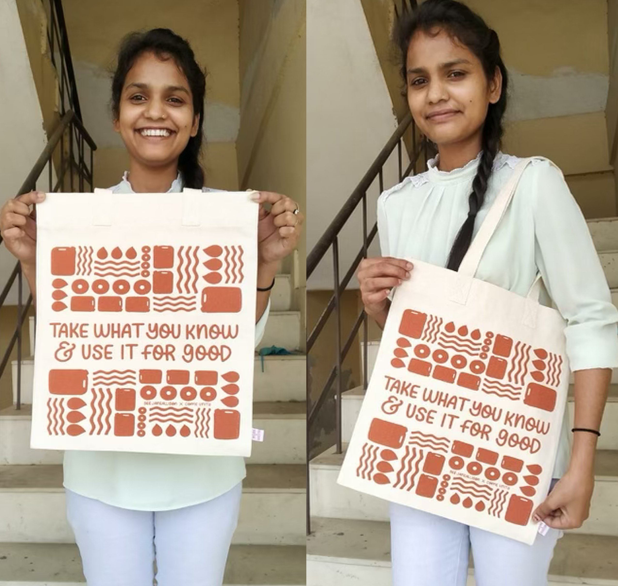 Two young women holding printed posters with geometric designs and motivational text on stairwell.