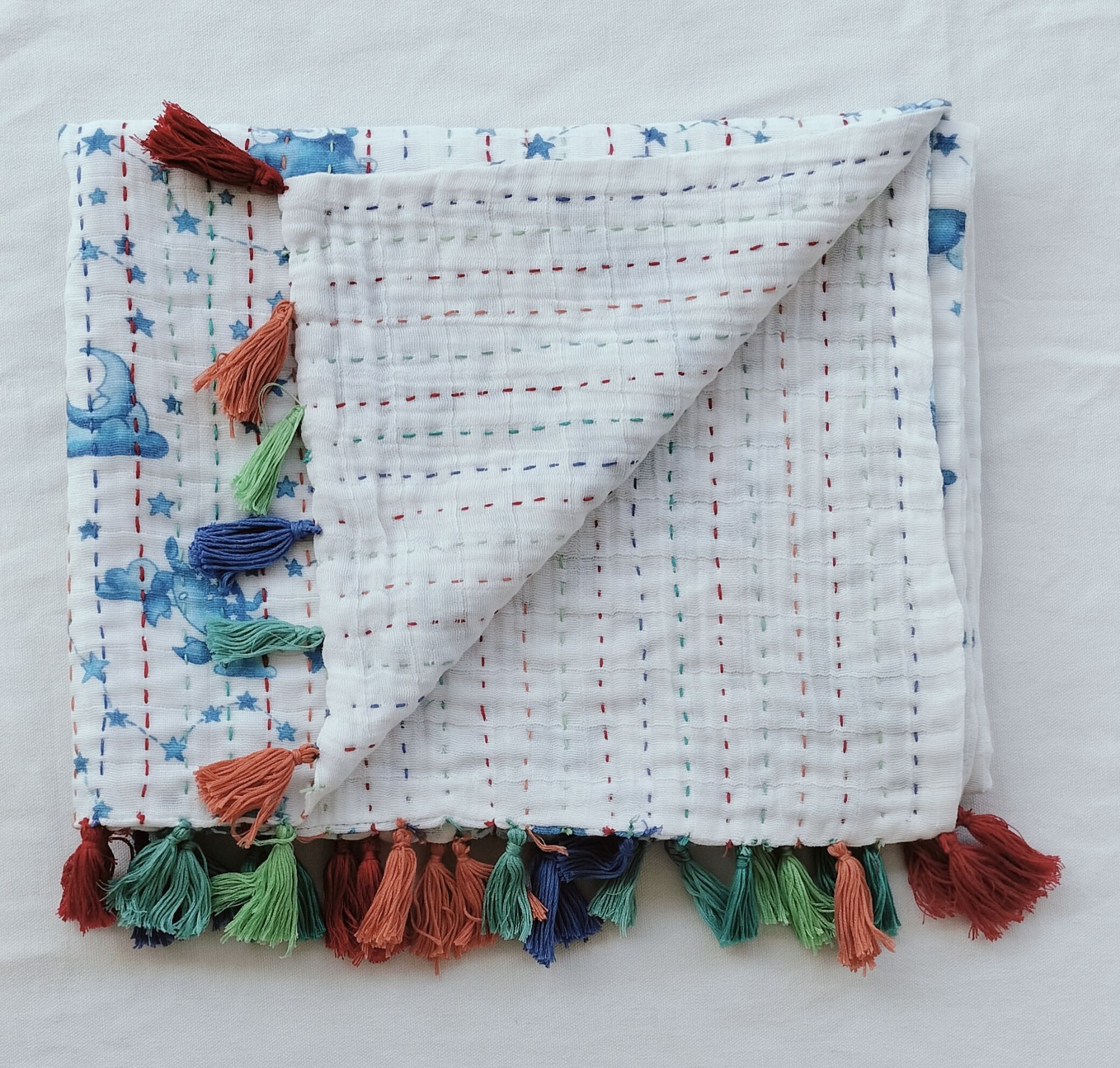 Handmade quilted fabric with stars and dashed stitching, decorated with colorful tassels.