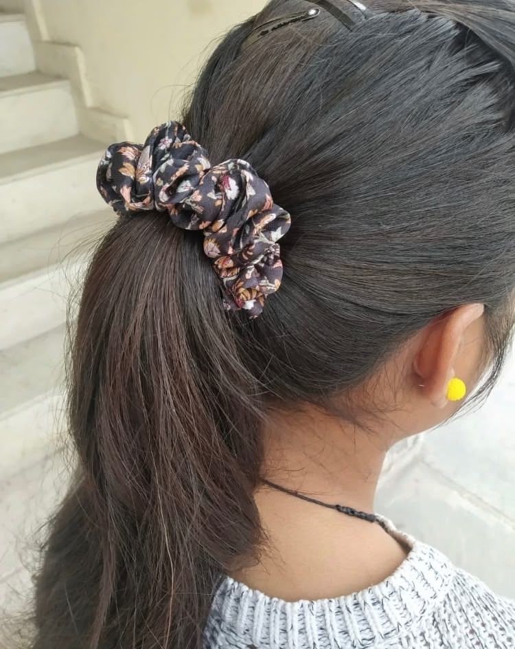 Girl wearing patterned scrunchie in dark hair ponytail, yellow earring visible.