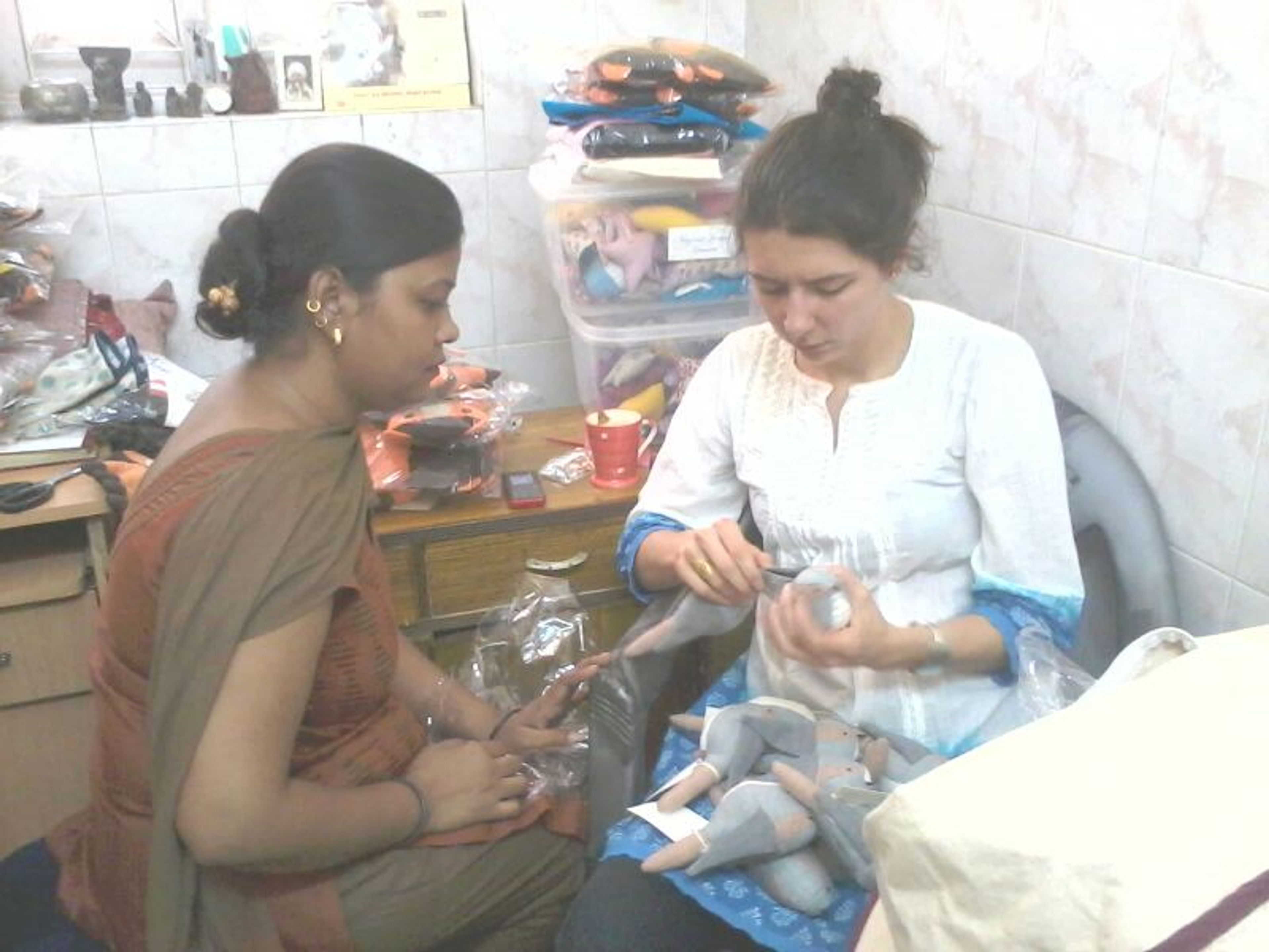 Two women preparing or packaging items in a small room workspace.