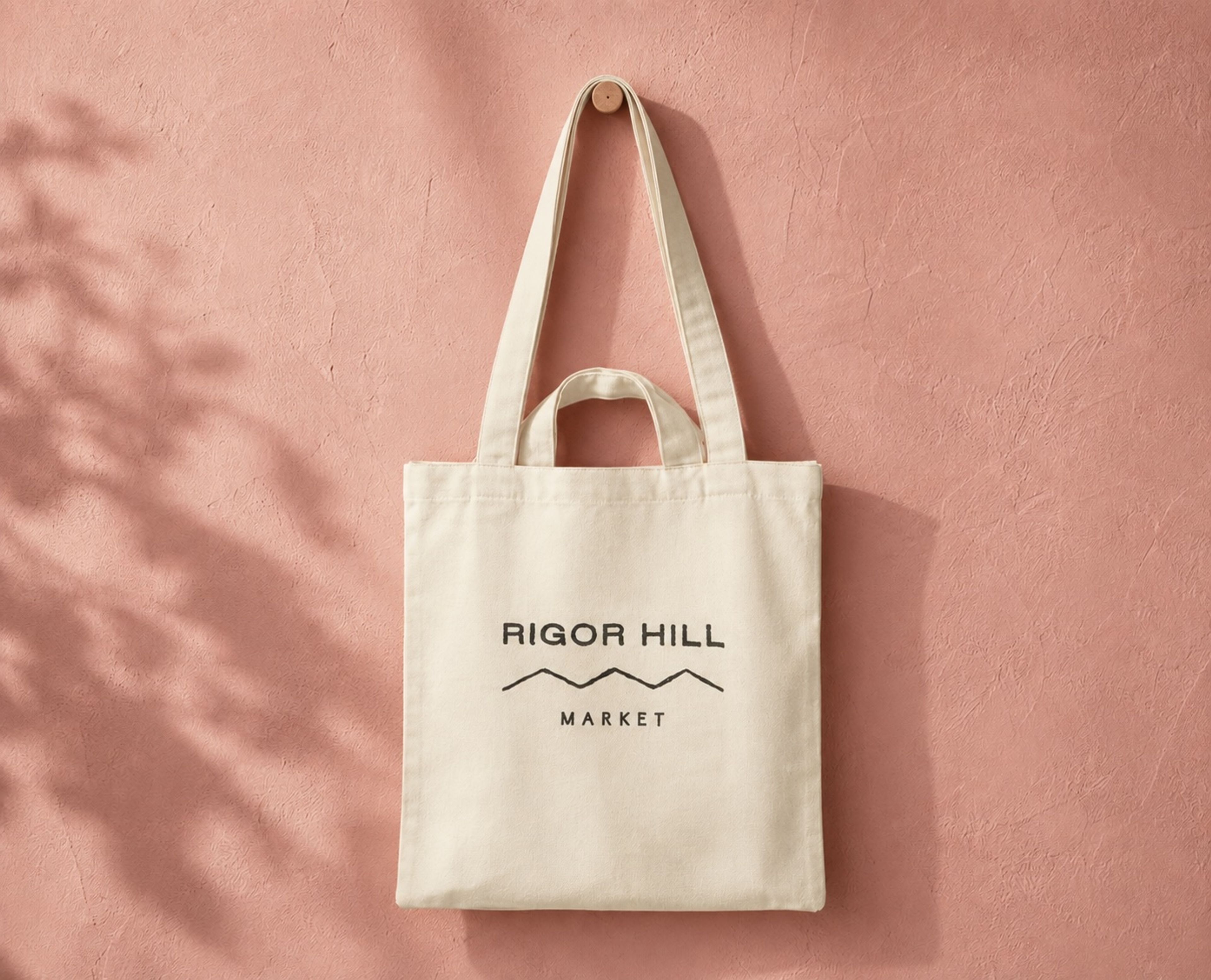 Rigor Hill Market display with apples, pears, and branded tote bags on wooden shelving.