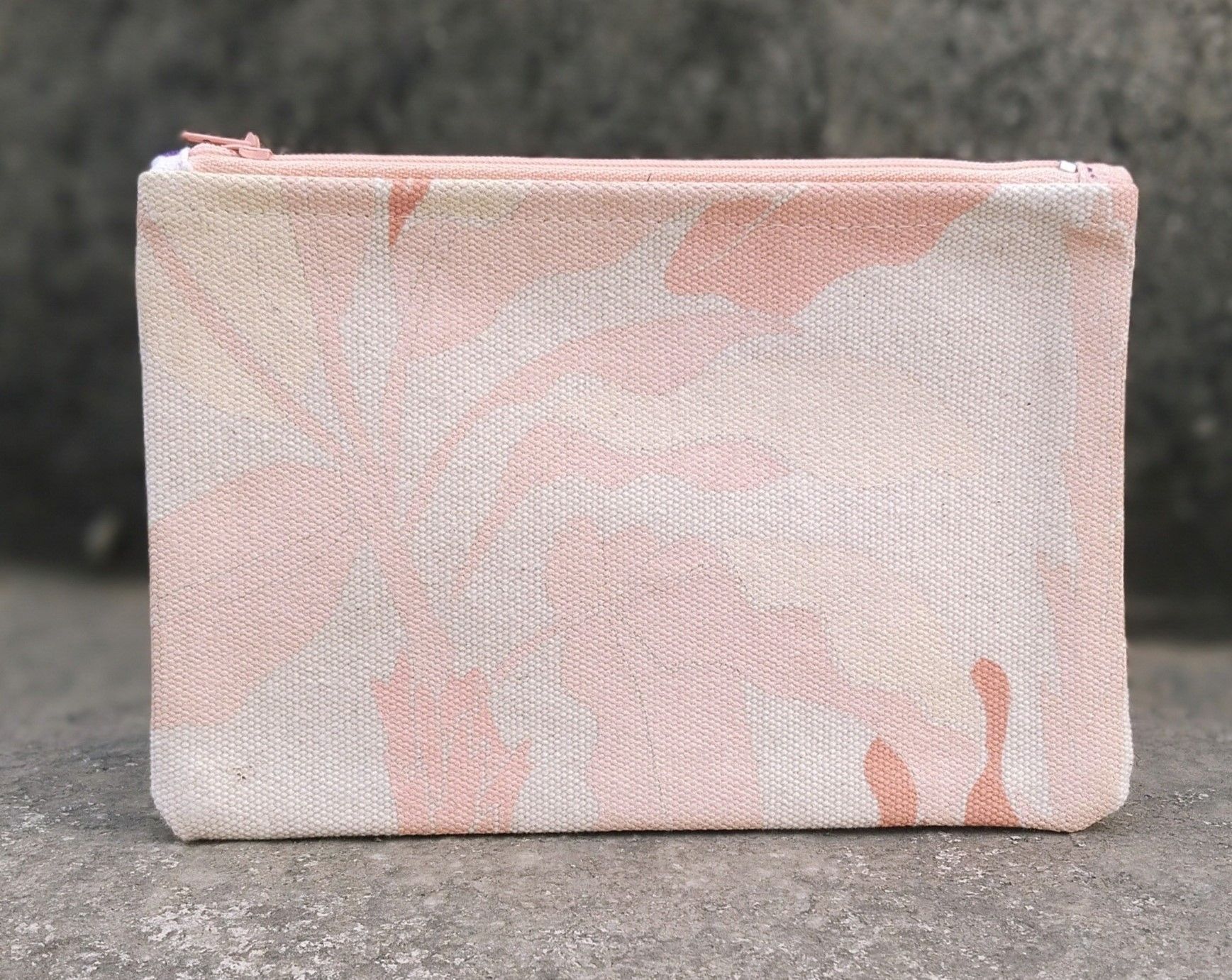Pink and cream canvas pouch with abstract brushstroke pattern on concrete surface.