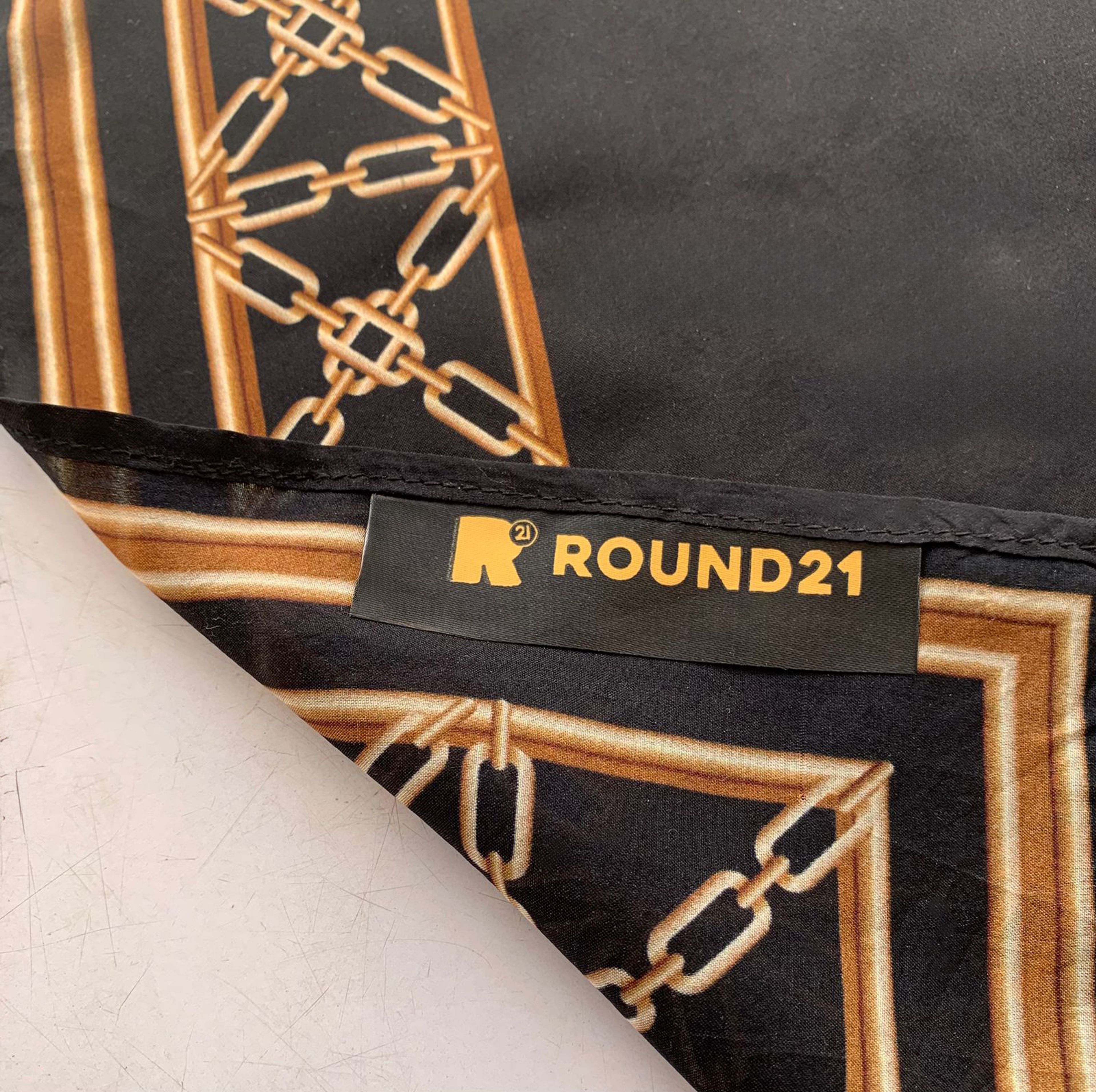 Black silk scarf featuring an orange WNBA logo and player silhouette in the center. The design is framed by an intricate gold chain-link border and includes the text 'The Game Grows On' at the bottom.