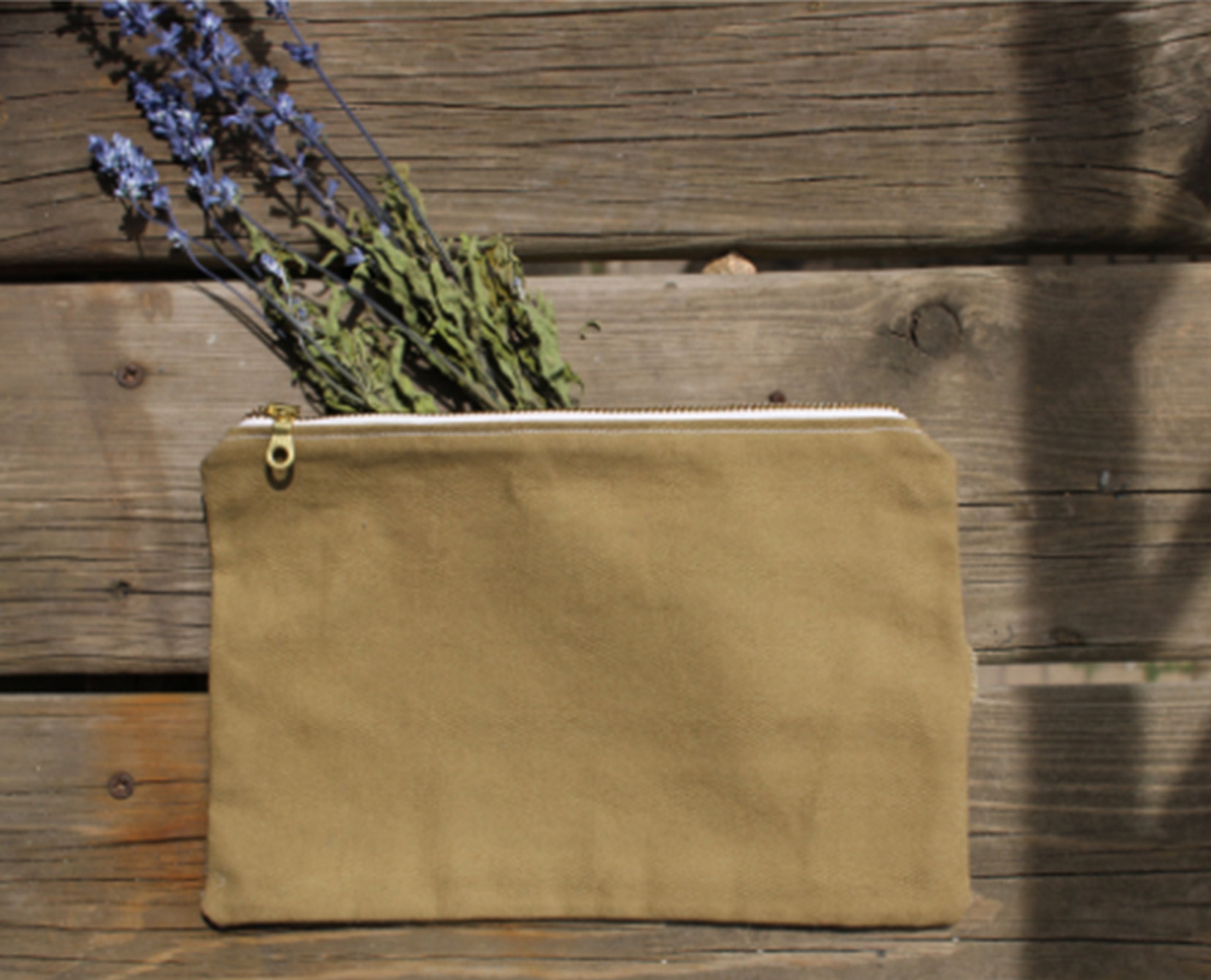 Beige canvas pouch with dried lavender flowers on wooden surface.