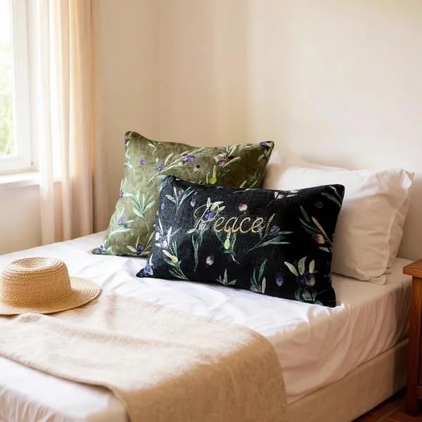 Bed with decorative pillows, straw hat, and white linens near a sunlit window.
