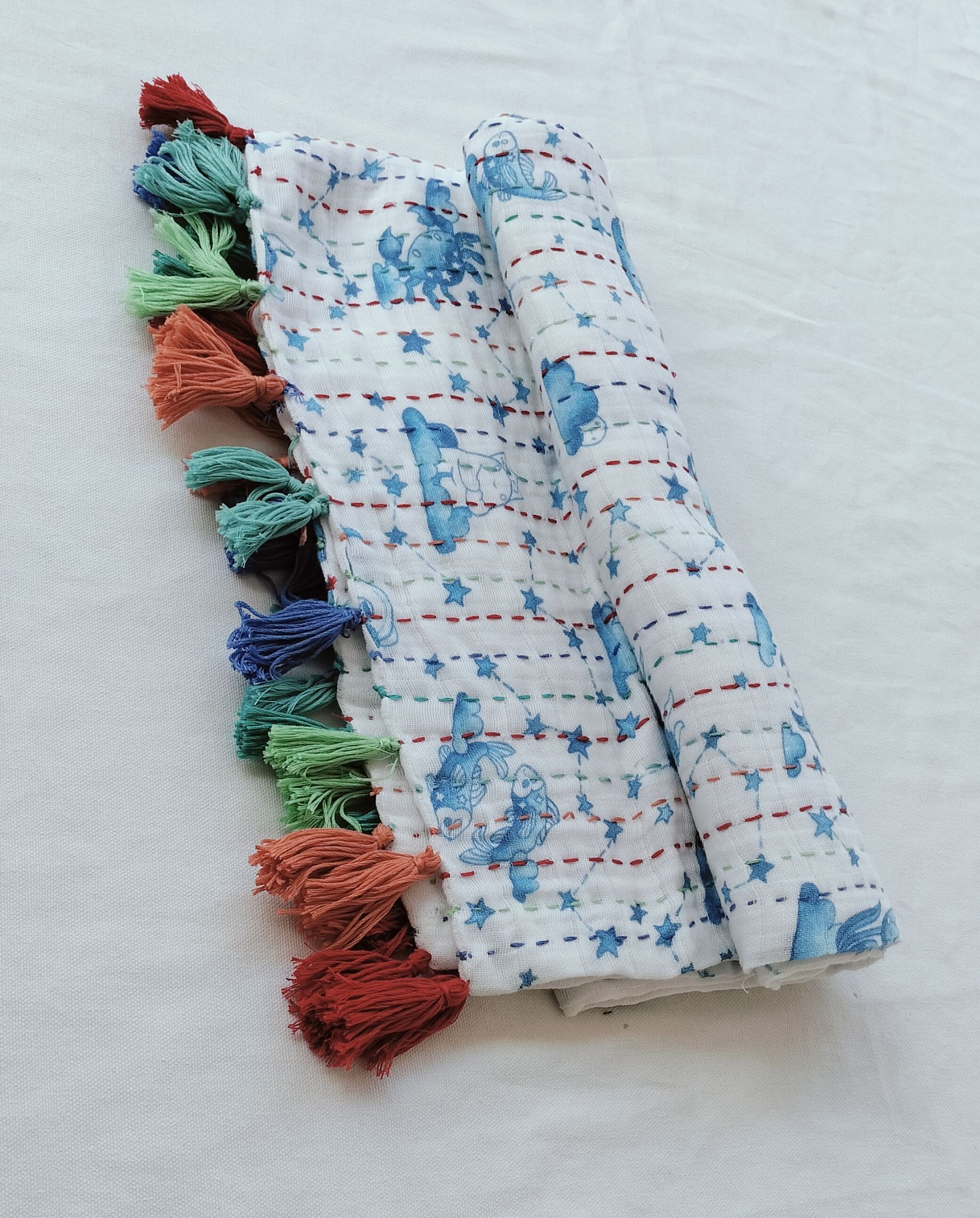 Rolled fabric with blue star pattern and colorful thread tassels attached along edge.