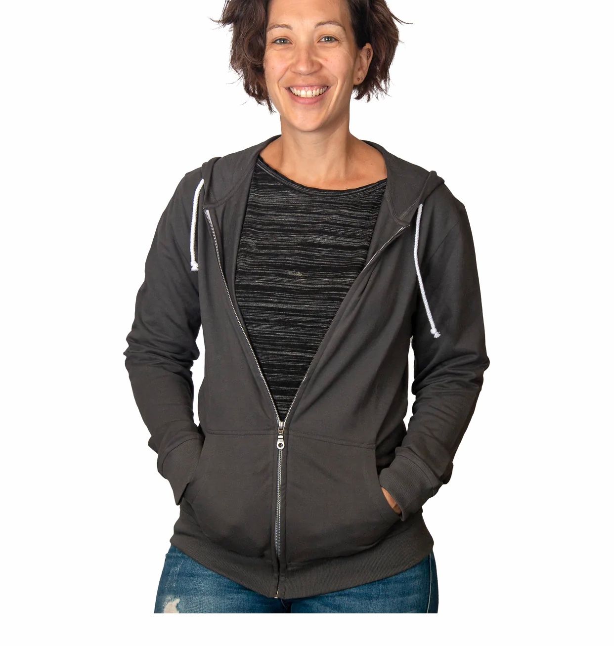 Woman wearing dark hoodie and striped shirt, smiling at camera against white background.