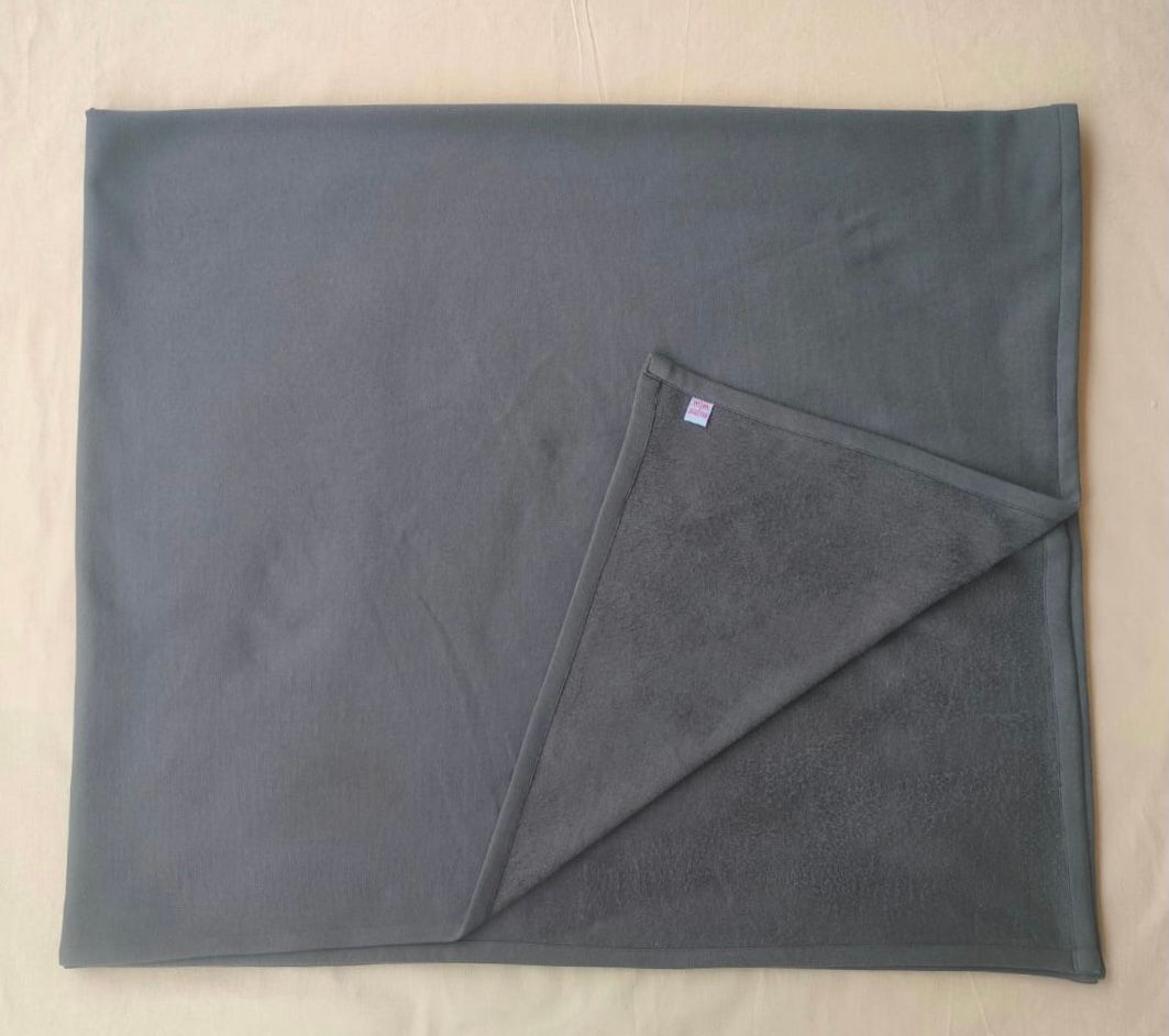 Gray fleece blanket with corner folded back, showing lighter underside on beige surface.